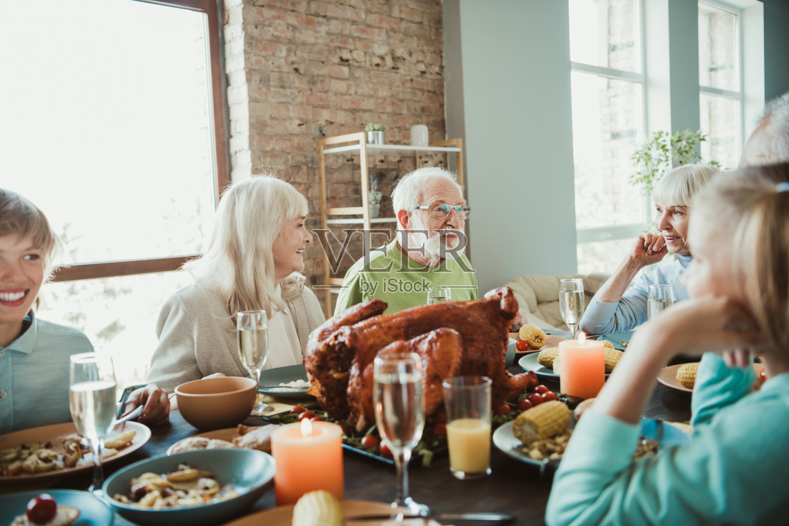 家人围坐在餐桌旁享用感恩节盛宴，祖父母、孙辈和朋友们分享着爱与感激之情。照片摄影图片