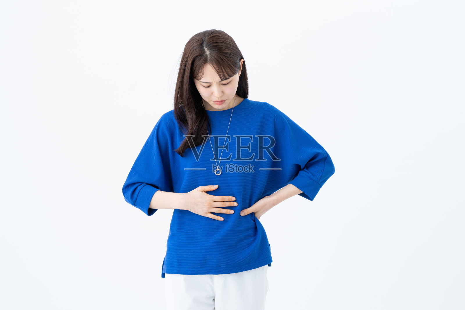 一位年轻女性正担忧地抚摸着自己的腹部照片摄影图片