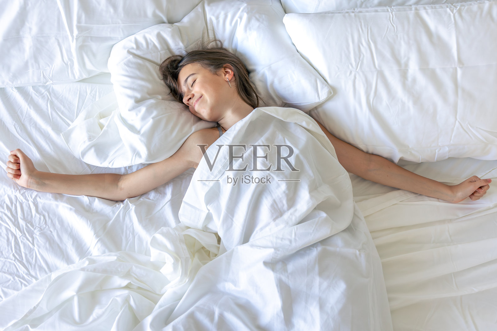 女孩微笑着醒来伸懒腰，充满早晨的活力。照片摄影图片