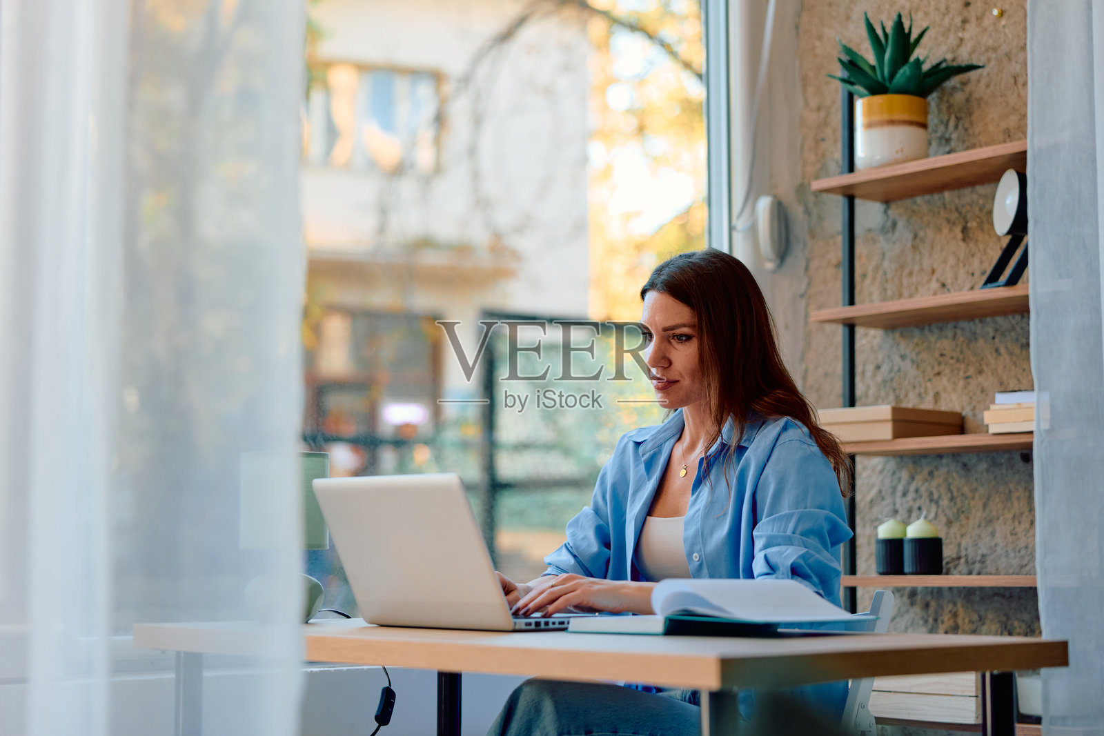 女性自由职业者在家里的办公室书桌上用笔记本电脑工作照片摄影图片