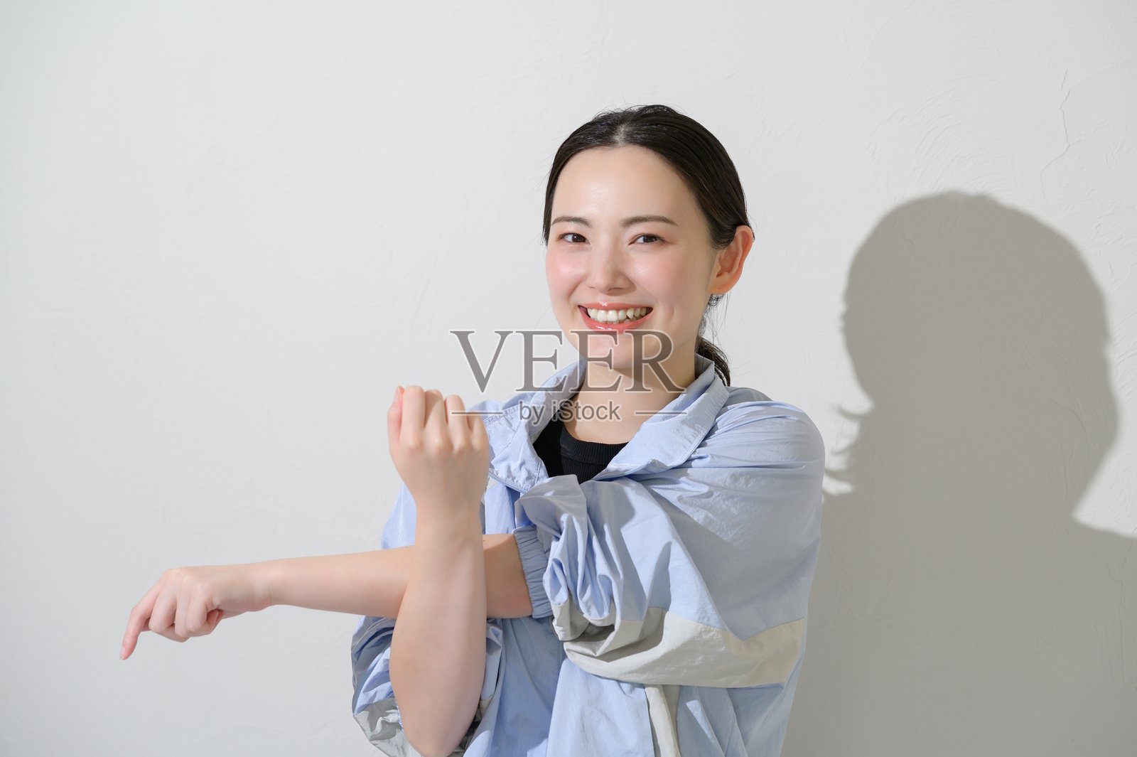 身着运动服的日本女性在白色背景上伸展身体照片摄影图片