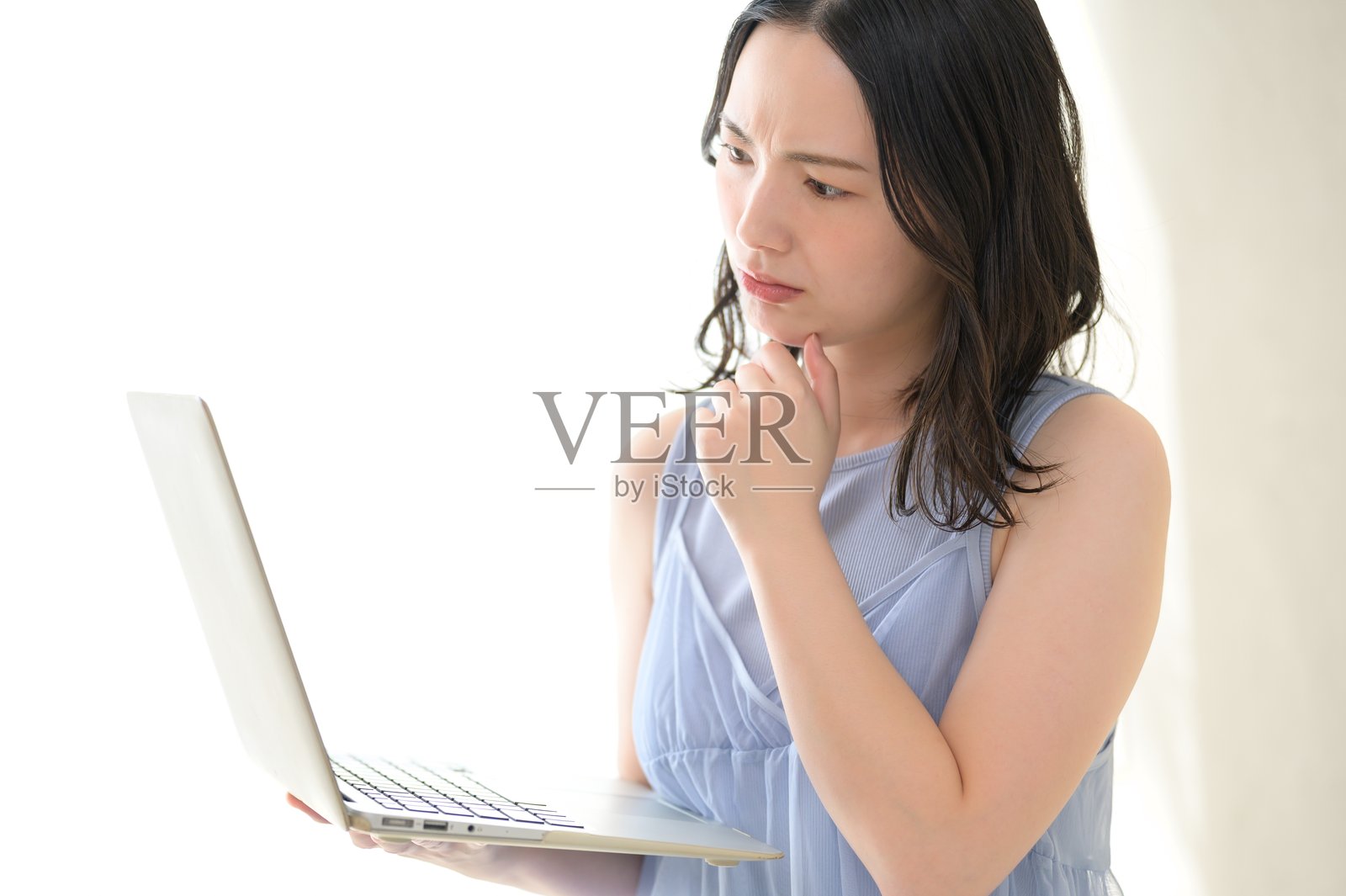 一位日本女性在房间里看着电脑，显得很担忧照片摄影图片