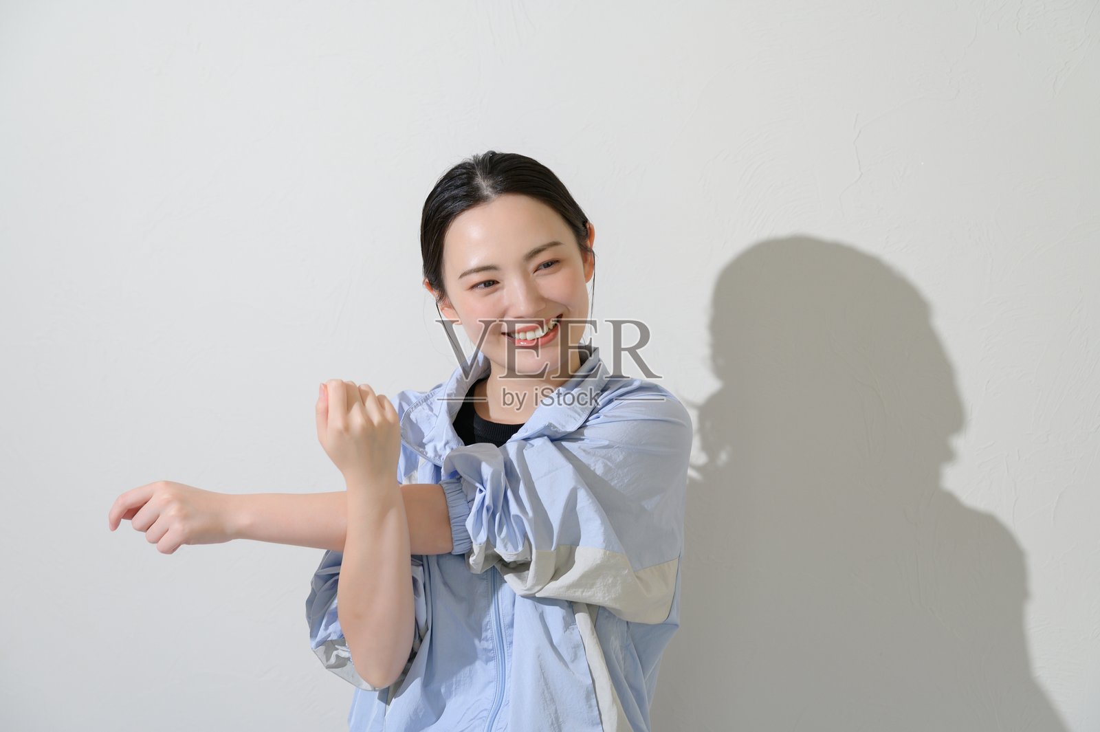 身着运动服的日本女性在白色背景上伸展身体照片摄影图片