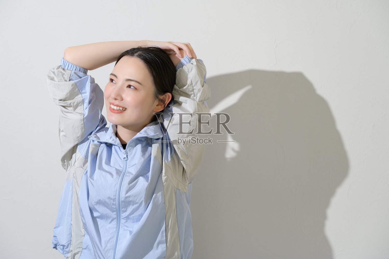 身着运动服的日本女性在白色背景上伸展身体照片摄影图片