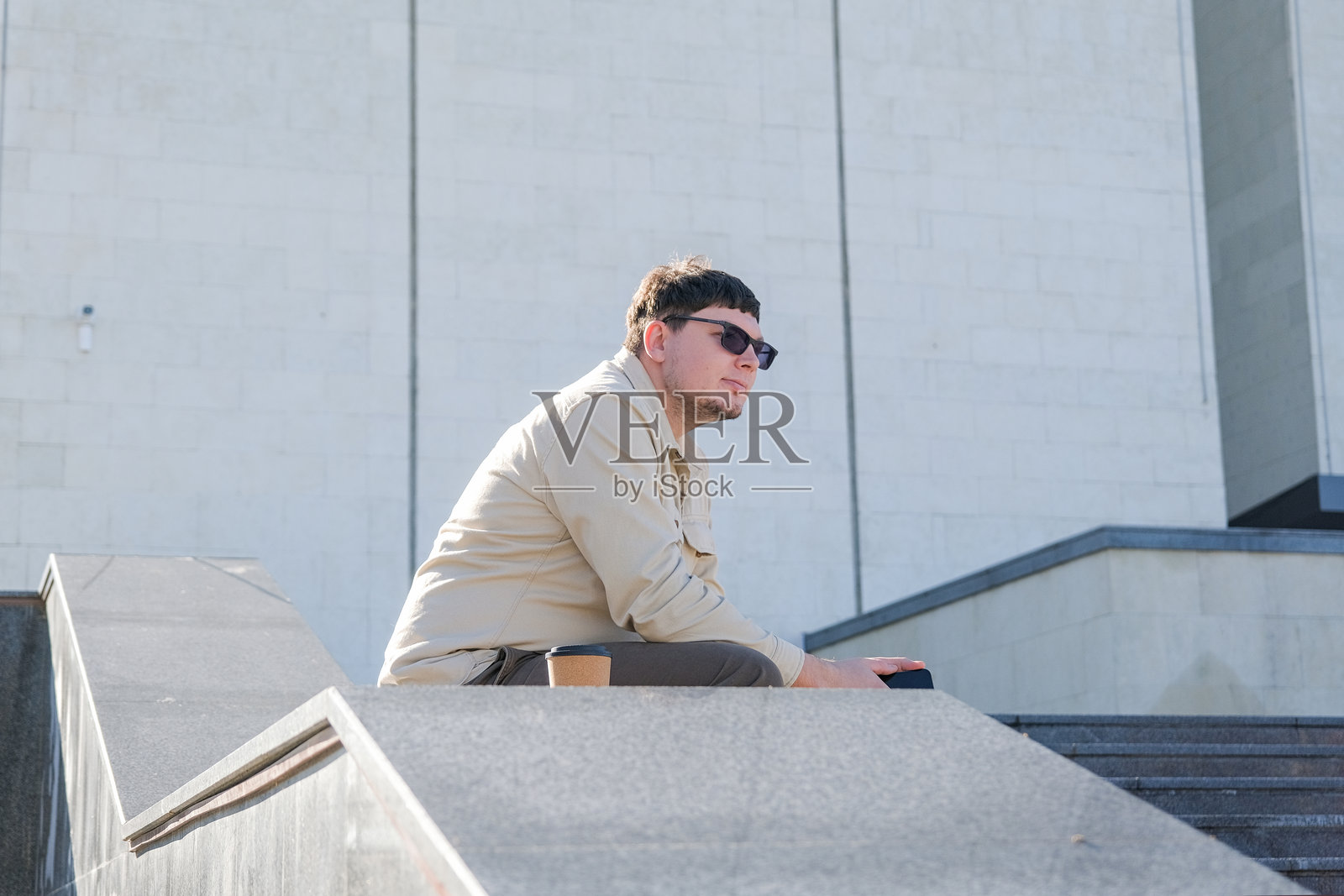 严肃的中年自由职业者，身着休闲装，坐在楼梯上使用智能手机。照片摄影图片