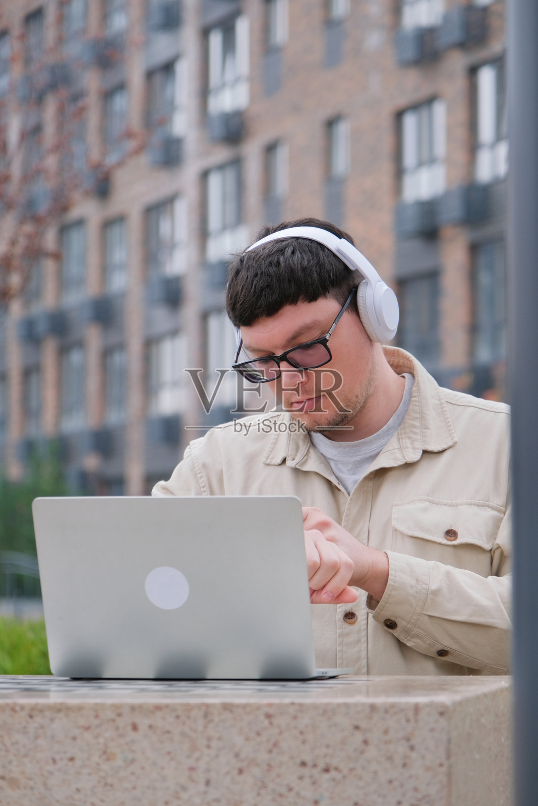 一位穿着休闲装的中年男子，职业自由工作者，正在街边使用笔记本电脑照片摄影图片
