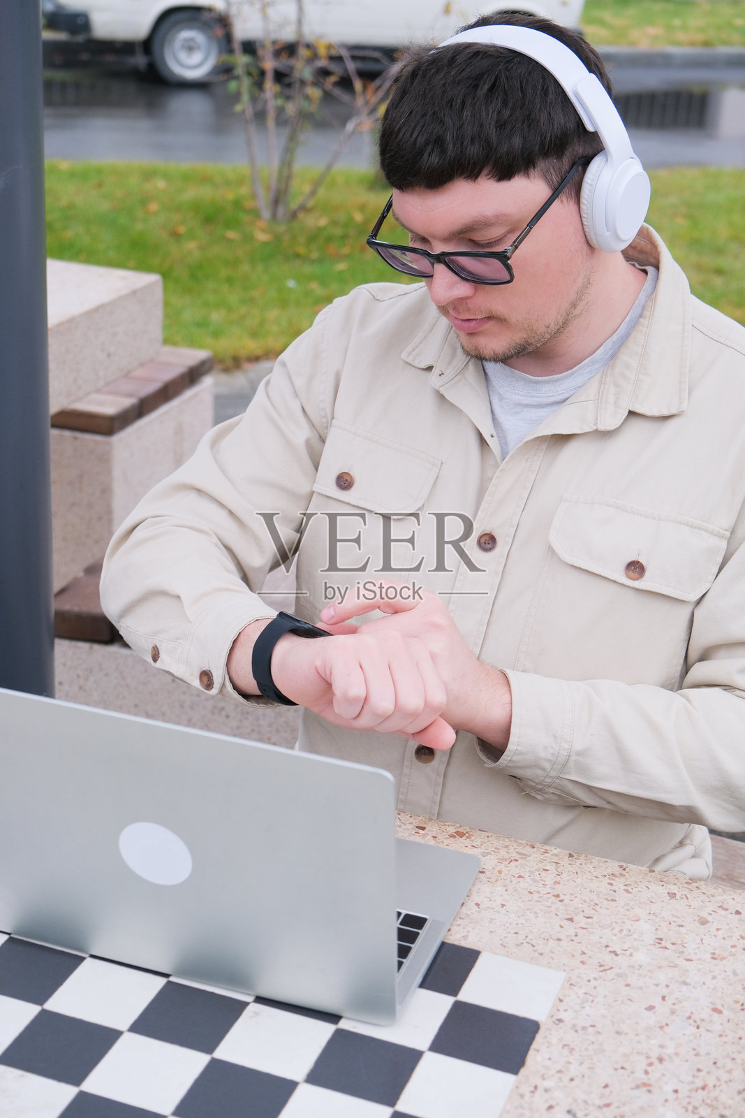 一位穿着休闲服的中年男子，职业自由职业者，正在街上使用笔记本电脑照片摄影图片