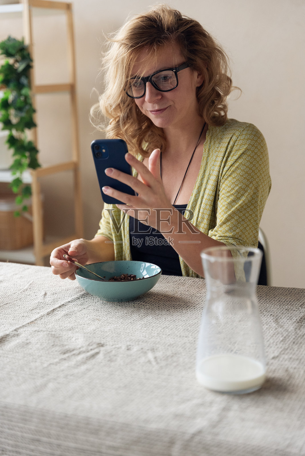 女子在家吃早餐时使用智能手机照片摄影图片