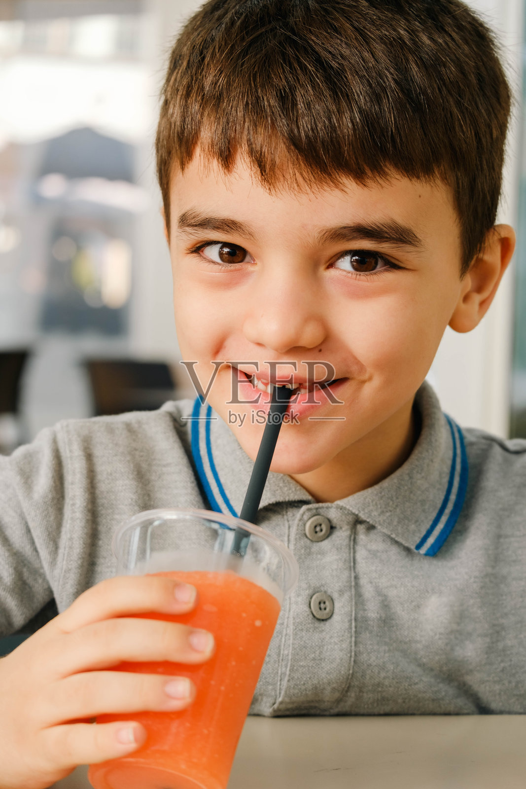 一个小男孩正用吸管喝一杯果汁照片摄影图片