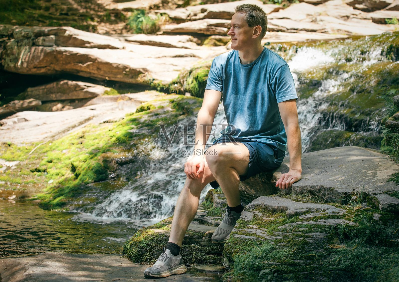 男人在森林里的瀑布旁放松照片摄影图片