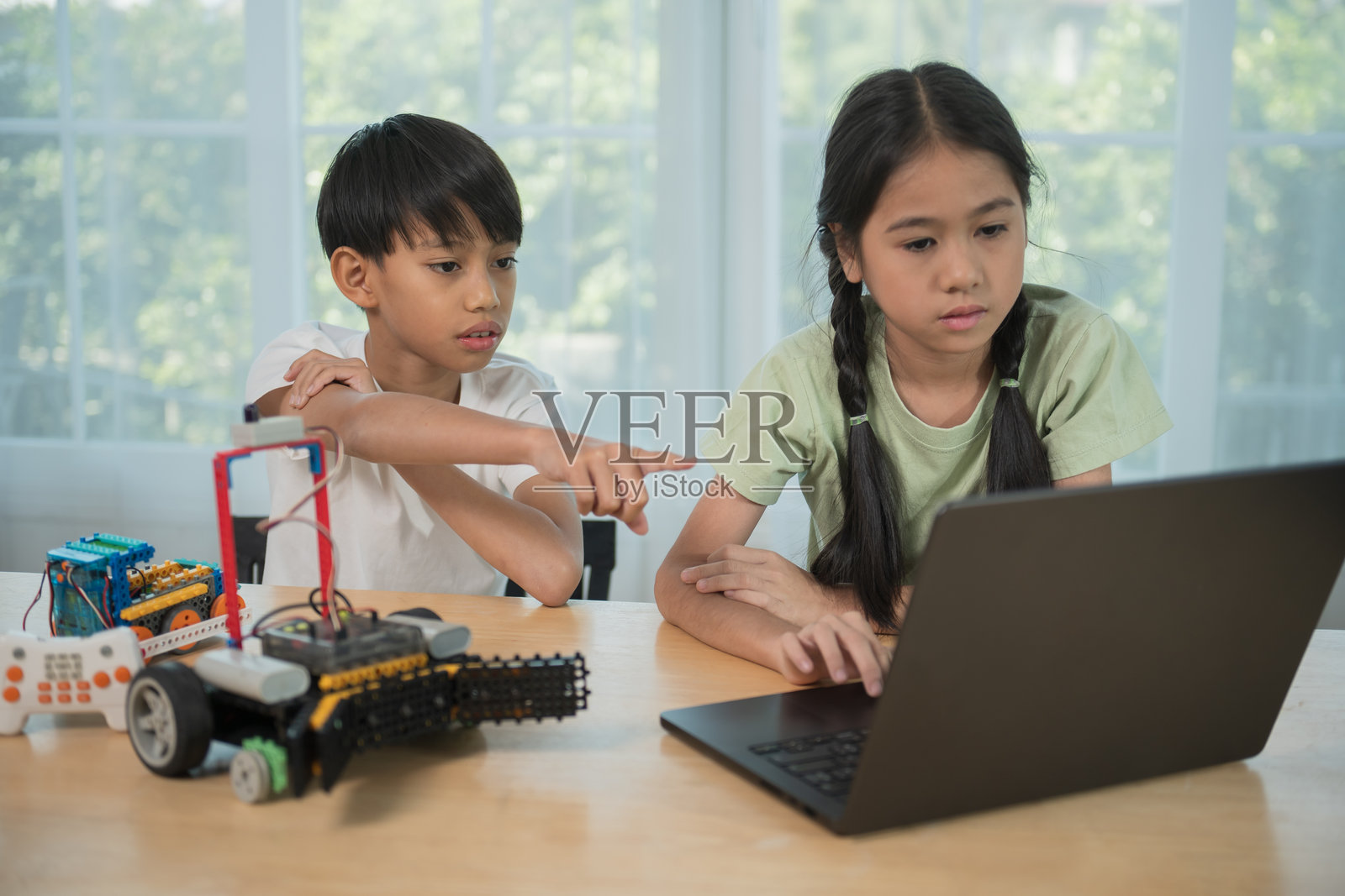 孩子在桌子上玩积木，同时用笔记本电脑打字，孩子用多彩的塑料积木玩耍和搭建。照片摄影图片