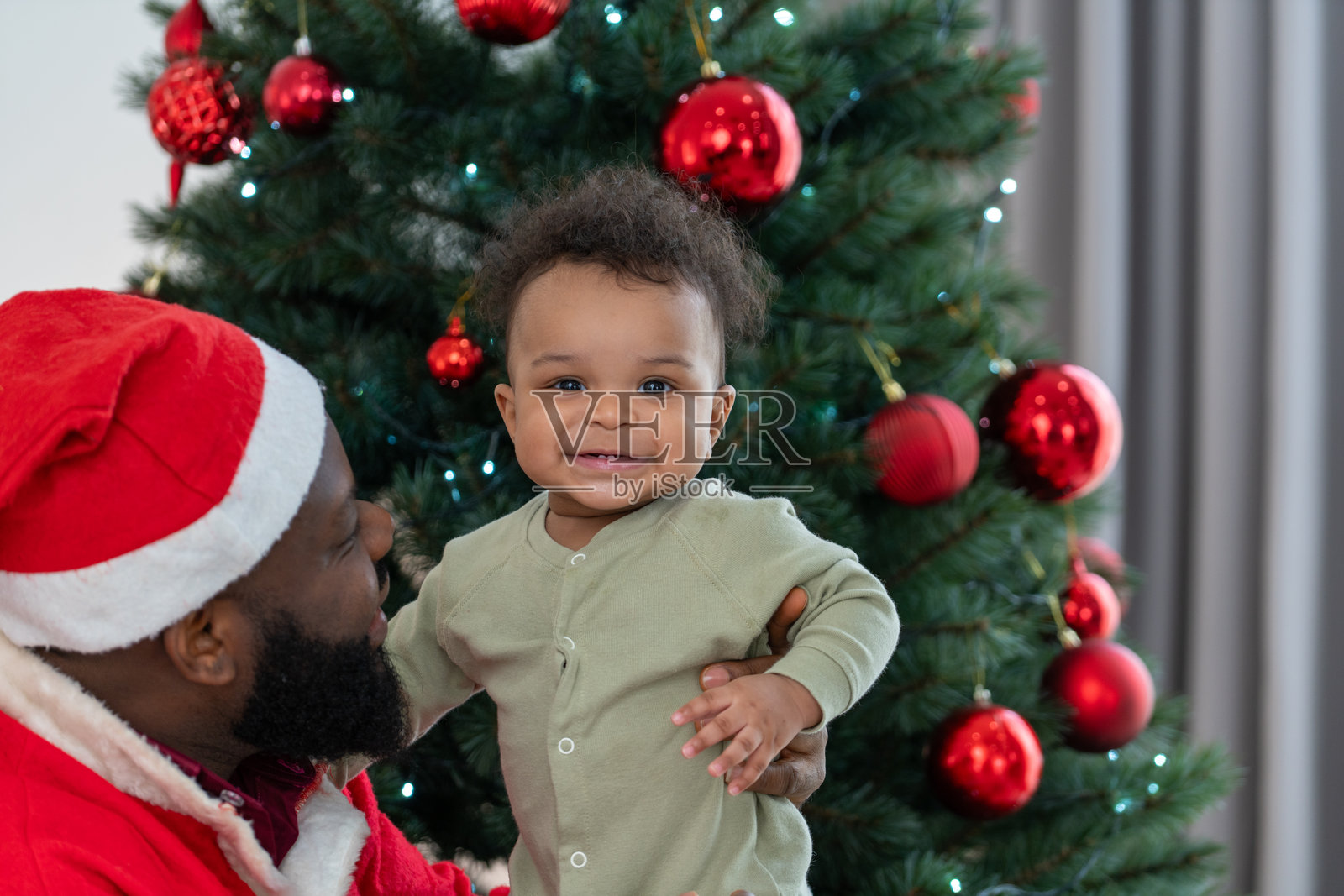 穿着圣诞服装的父亲抱着微笑的婴儿，庆祝圣诞快乐的节日照片摄影图片