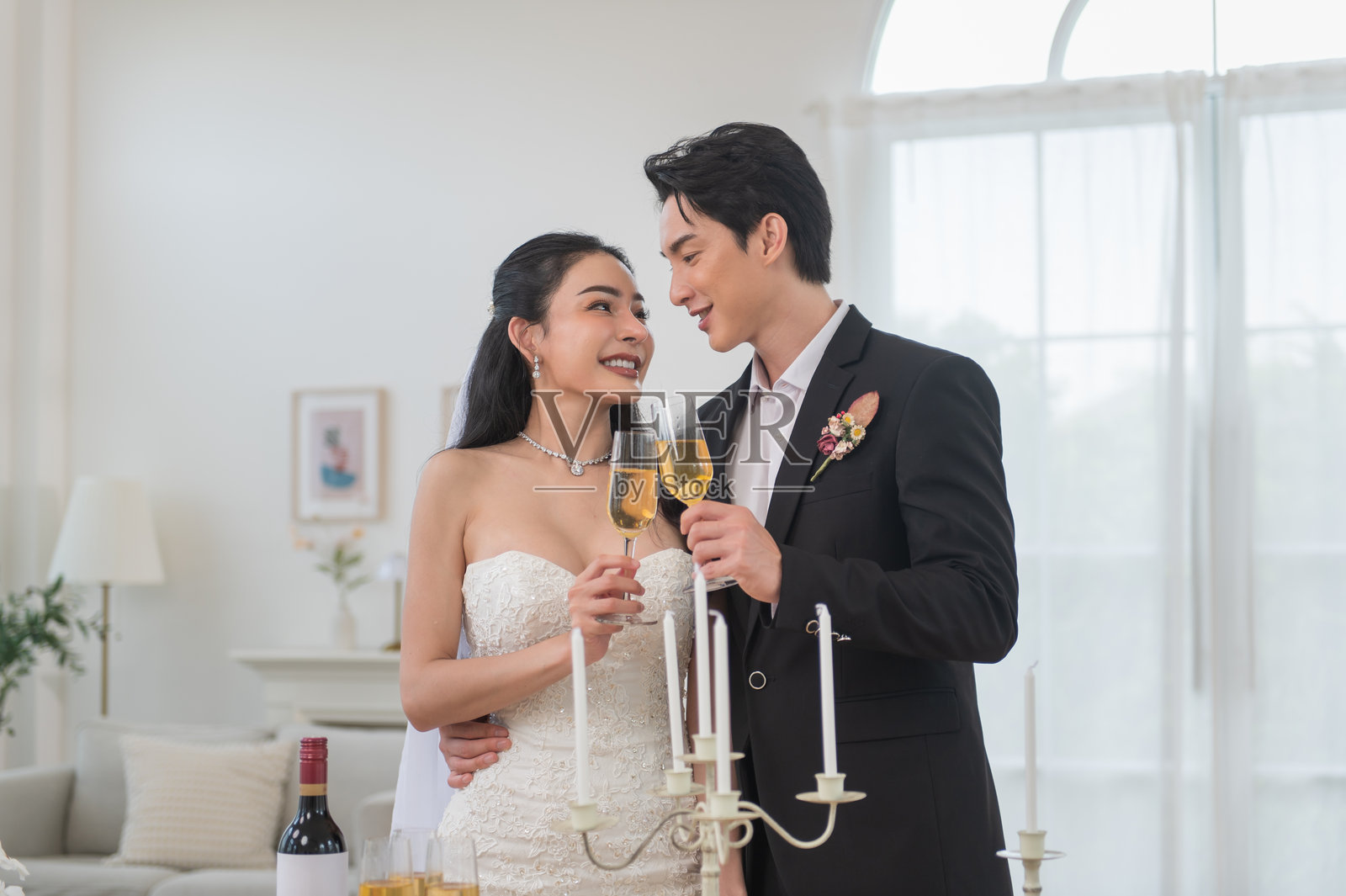 浪漫的亚洲新郎新娘在室内用香槟庆祝婚礼照片摄影图片