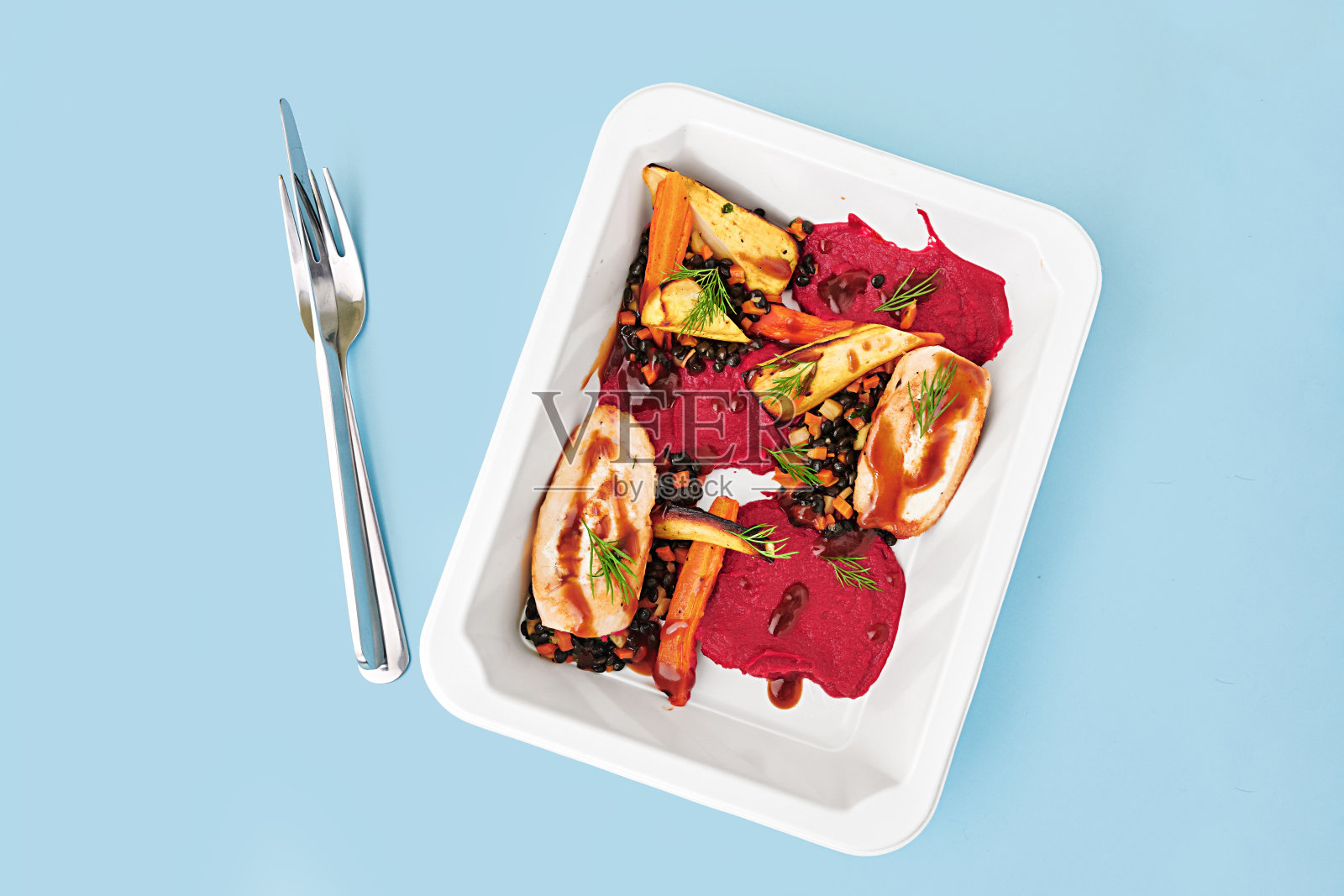 浅蓝色背景上，白色容器盛装着色彩缤纷的美味佳肴。照片摄影图片