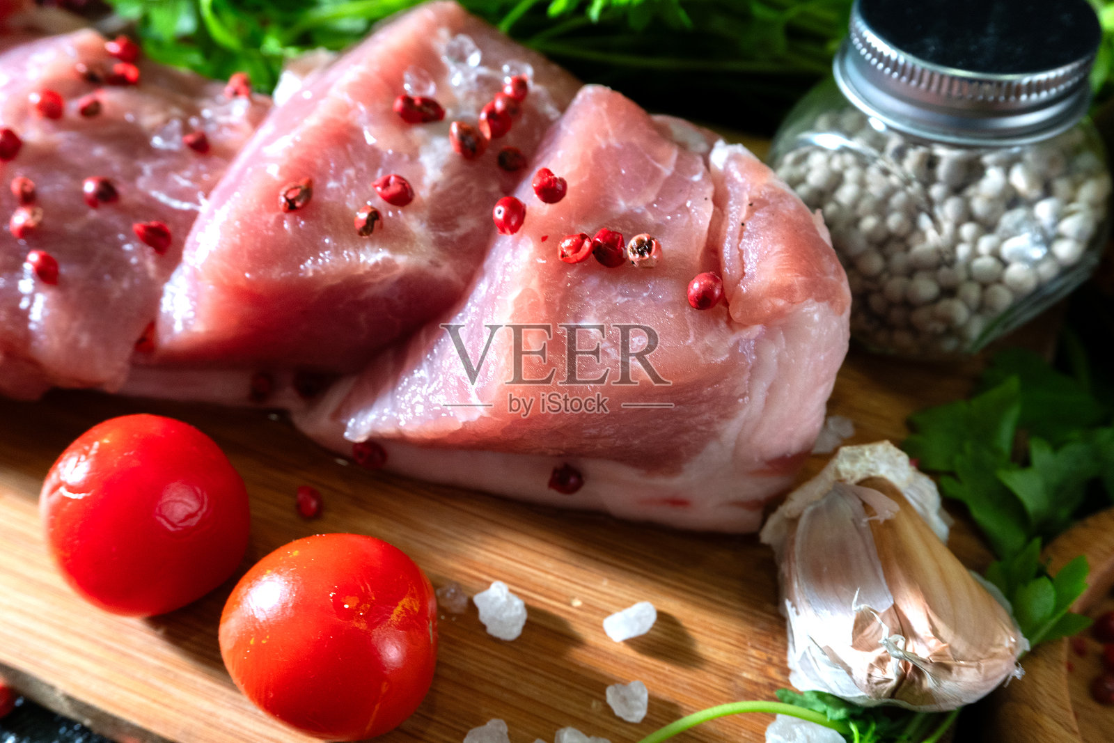 切肉板上的生肉，配以番茄和欧芹照片摄影图片