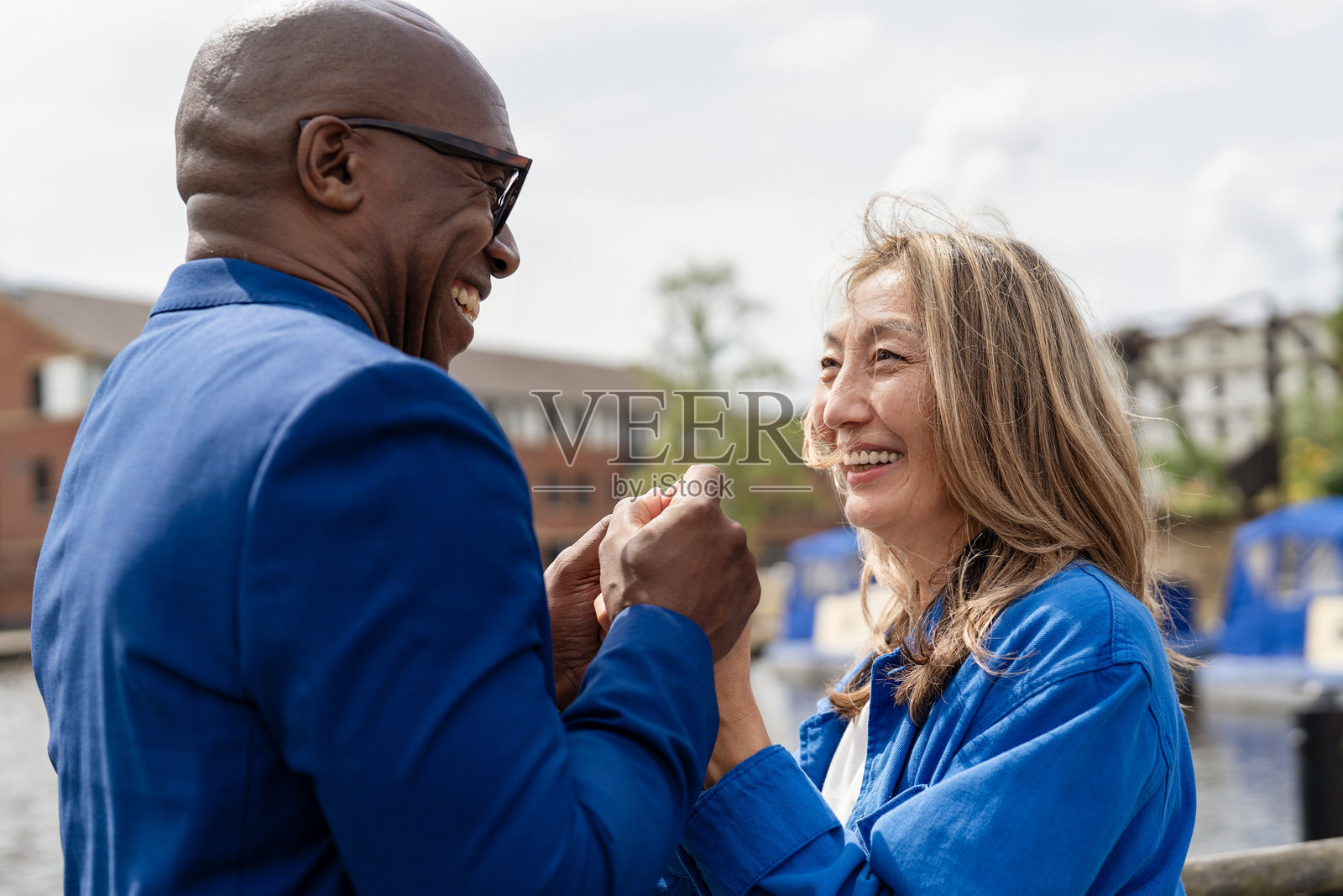 阳光明媚的午后，在繁华都市的滨水区，两位朋友共享着欢乐时光照片摄影图片