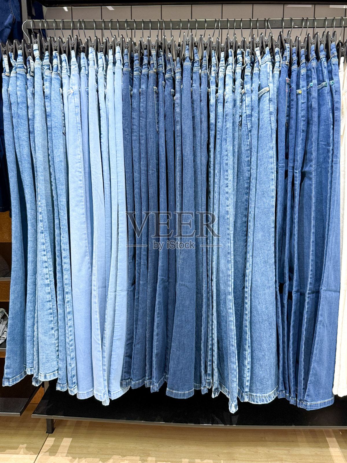 一排蓝色牛仔裤挂在架子上照片摄影图片