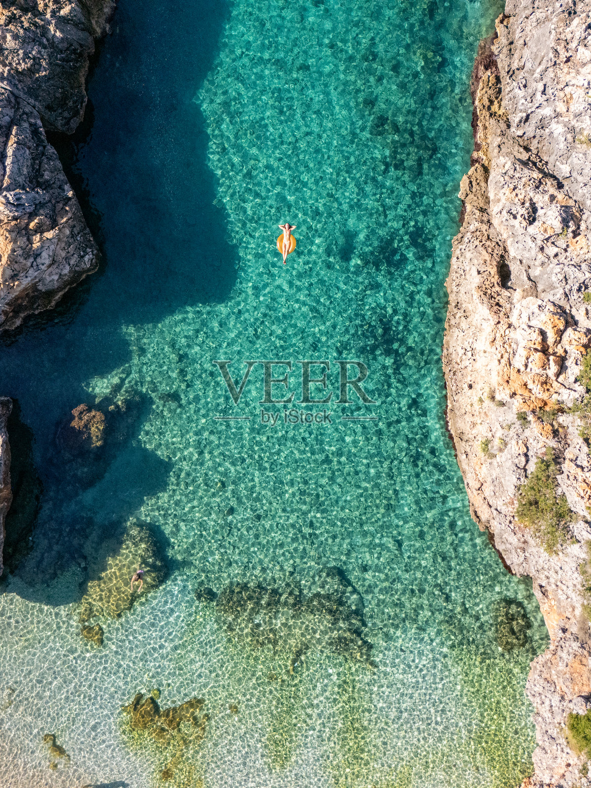 女子悠闲地漂浮在清澈的岩石海湾照片摄影图片