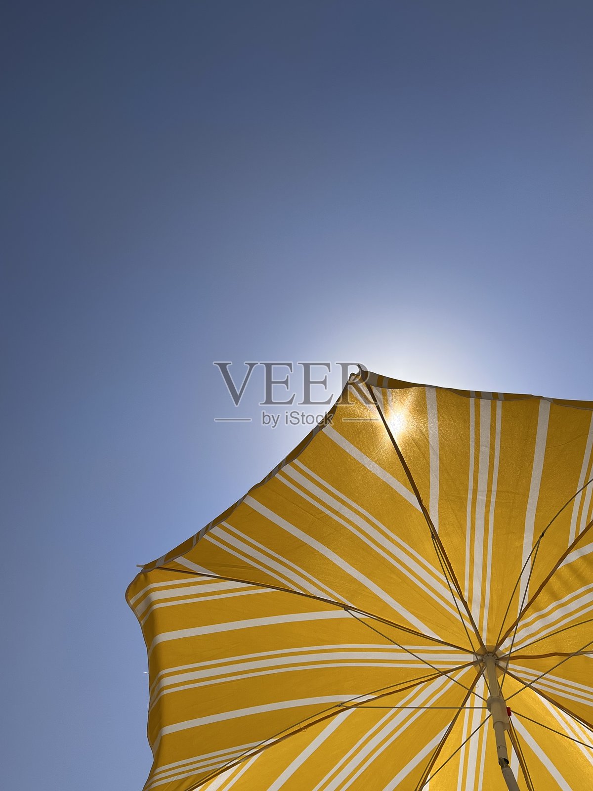 晴朗天空下，黄色的沙滩伞遮挡着阳光照片摄影图片