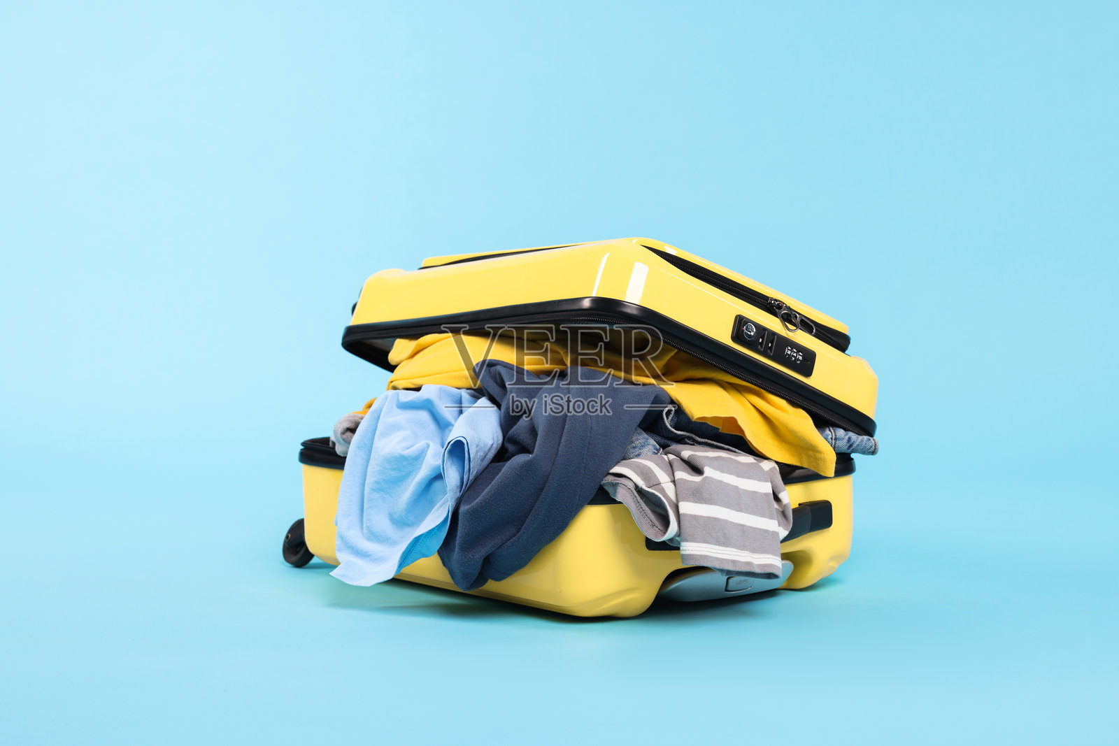 一个装满衣服的行李箱放在浅蓝色背景上照片摄影图片