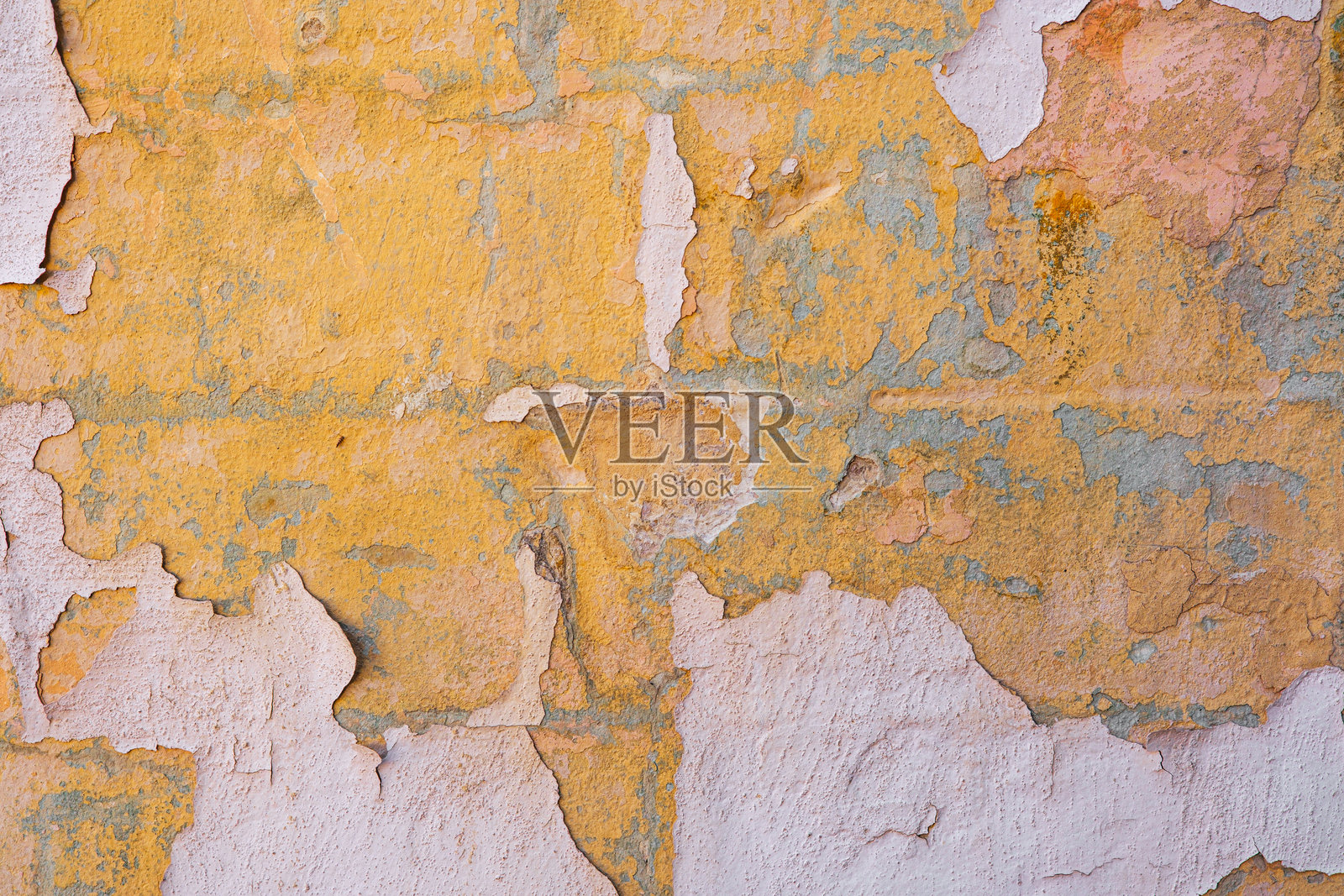 表面风化的粗糙老旧墙壁，剥落的油漆显露出黄粉色层照片摄影图片