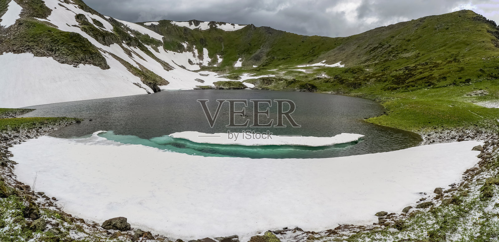 雪融化了。山峰、绿草和寒冷的湖泊照片摄影图片