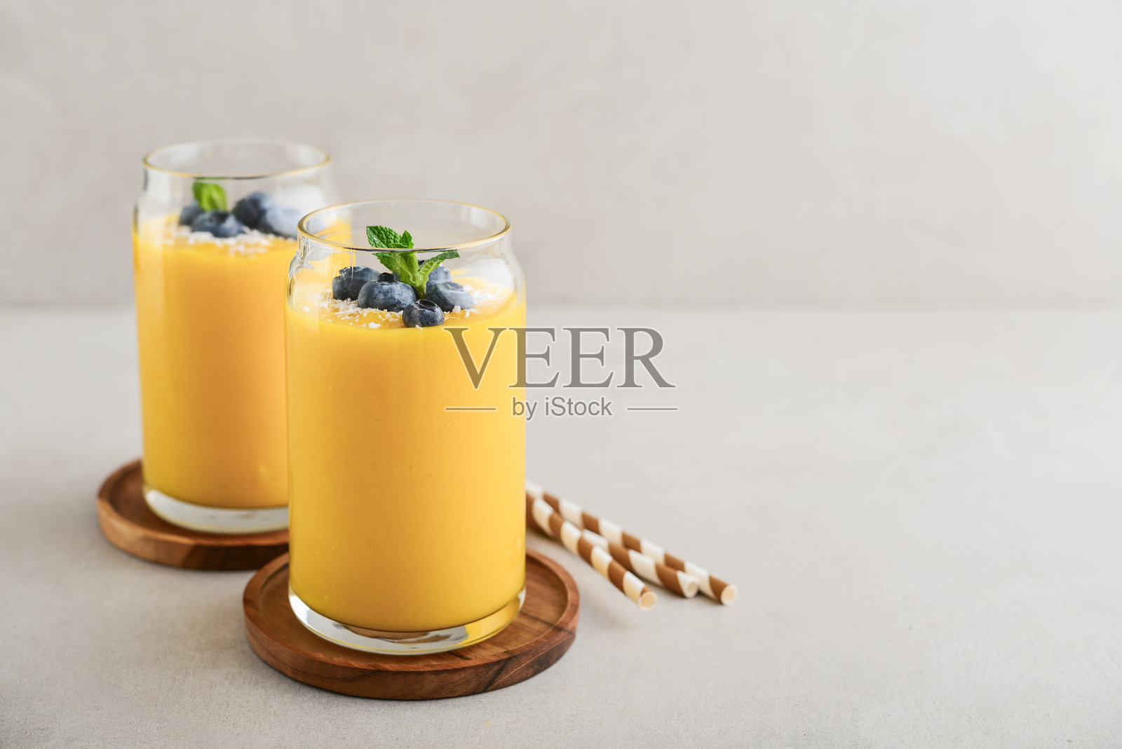 清爽健康的芒果冰沙，撒上椰子片和新鲜蓝莓照片摄影图片