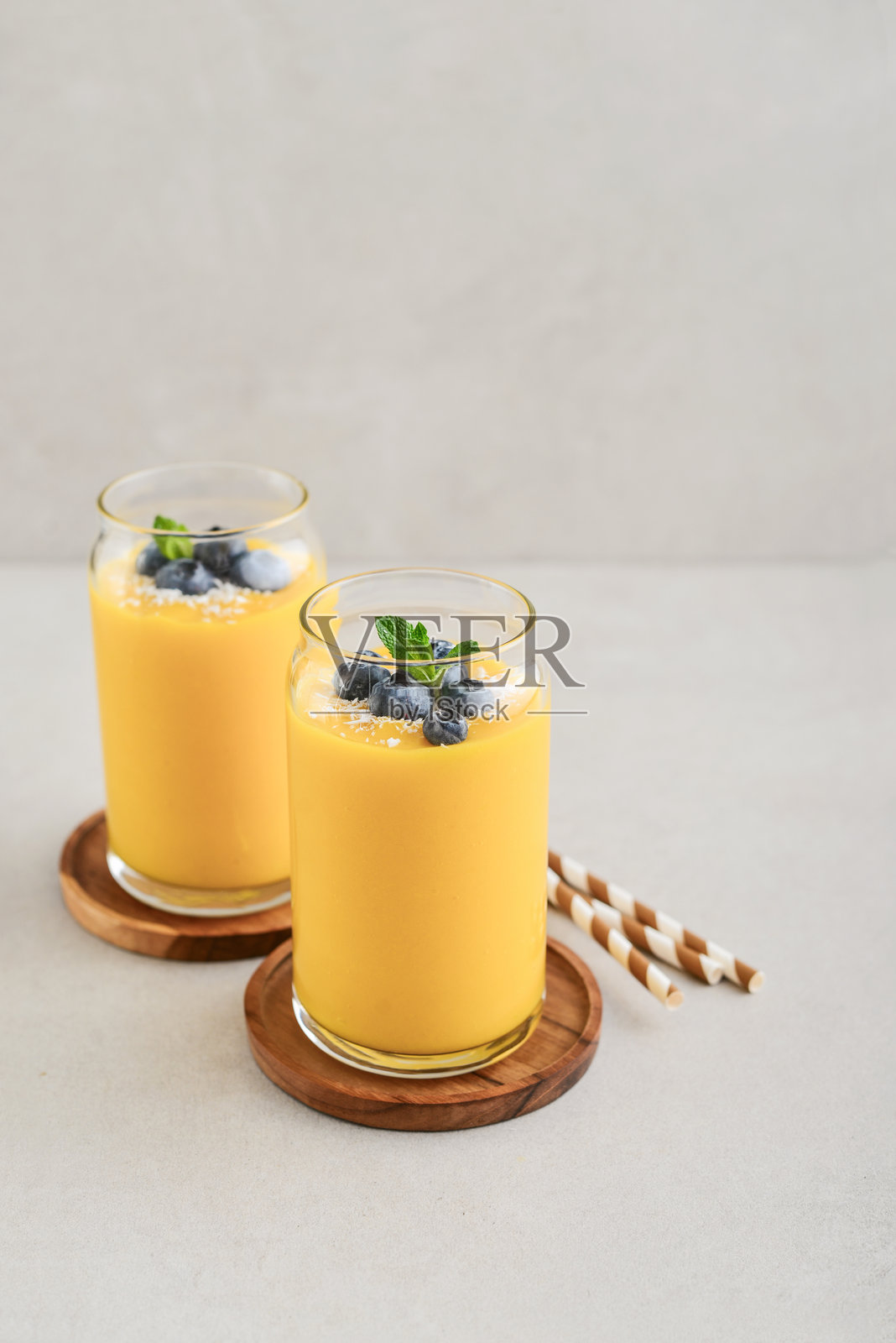 清爽健康的芒果冰沙，撒上椰子片和新鲜蓝莓照片摄影图片