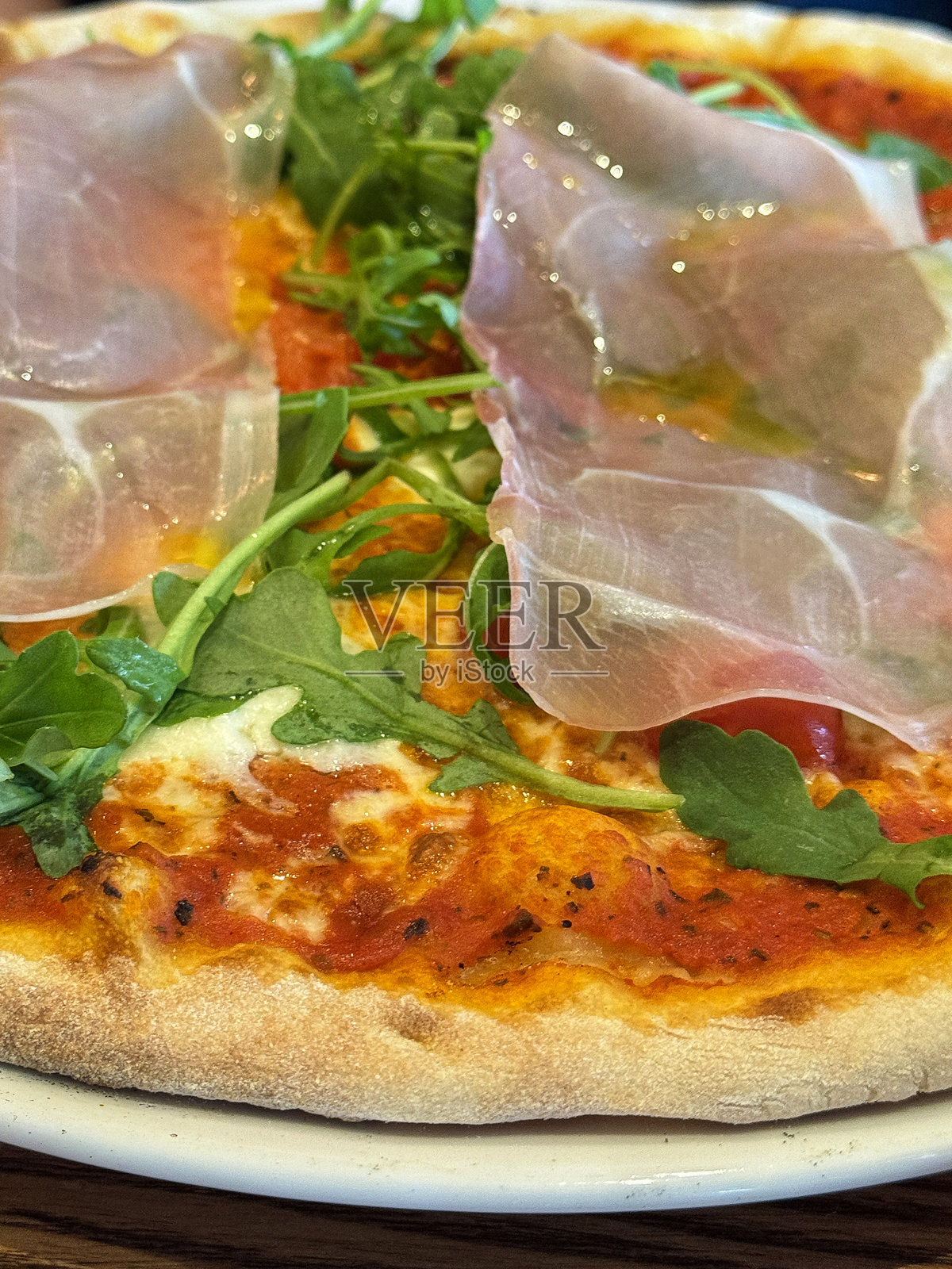 烤箱烤制的意大利披萨，配有帕尔马火腿、玛格丽特披萨、意大利熏火腿、芝麻菜、马苏里拉奶酪和新鲜罗勒照片摄影图片