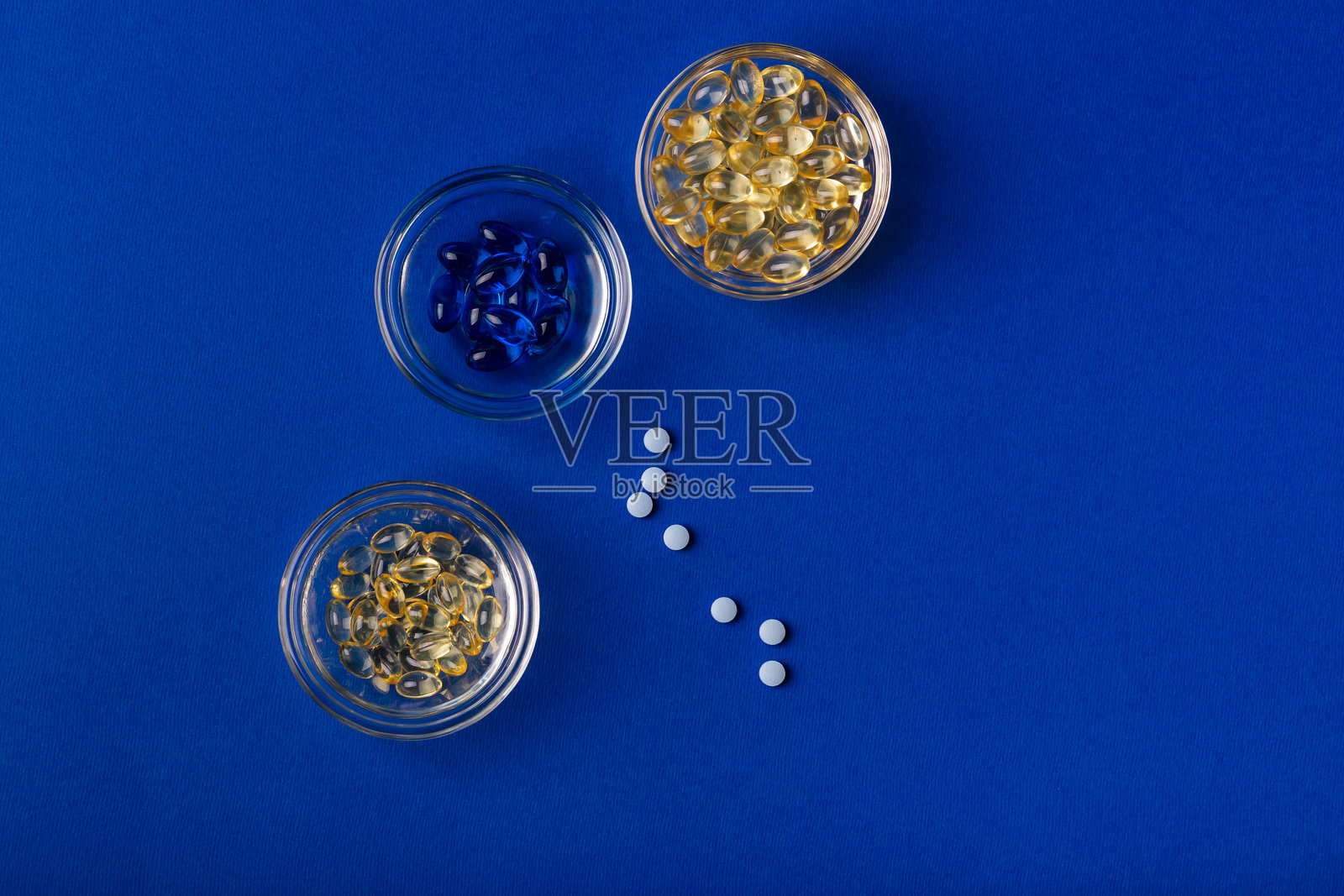 蓝色和黄色软胶囊，背景为蓝色。蓝色和黄色药丸。照片摄影图片