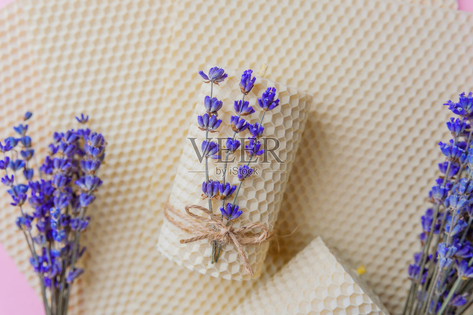 粉色背景上的蜂蜡蜡烛和薰衣草束照片摄影图片