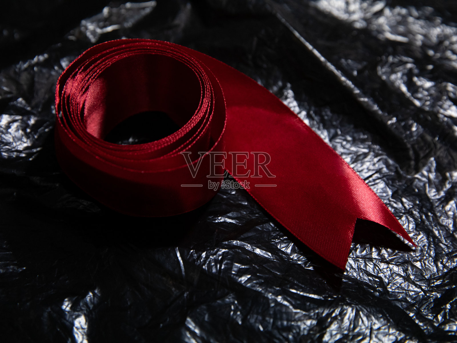 粗犷的红色丝带横跨在起皱的黑色背景上照片摄影图片