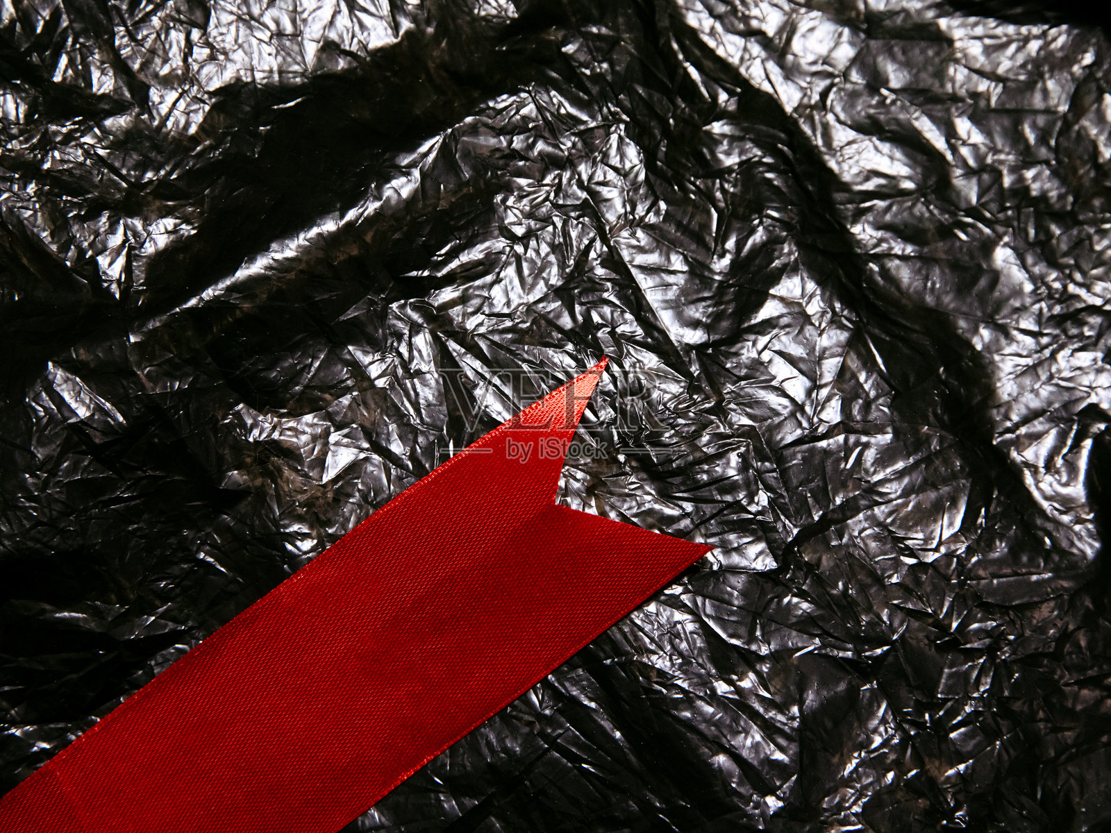 褶皱的黑色背景上有一条醒目的红色丝带照片摄影图片