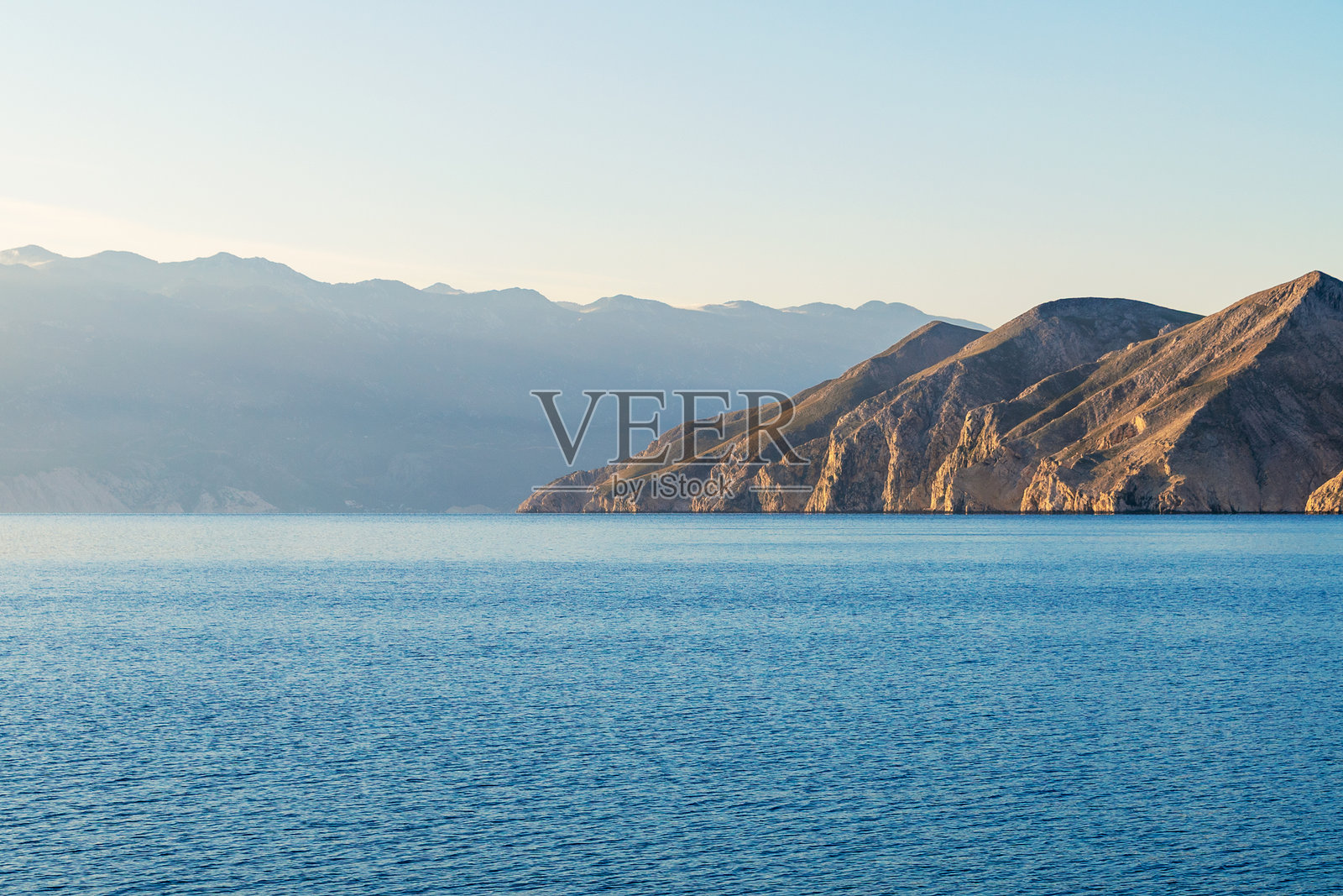 宁静的海岸风光，落日时分，岩石山丘与宁静的蓝色大海。克罗地亚普尔维奇岛的景色。照片摄影图片