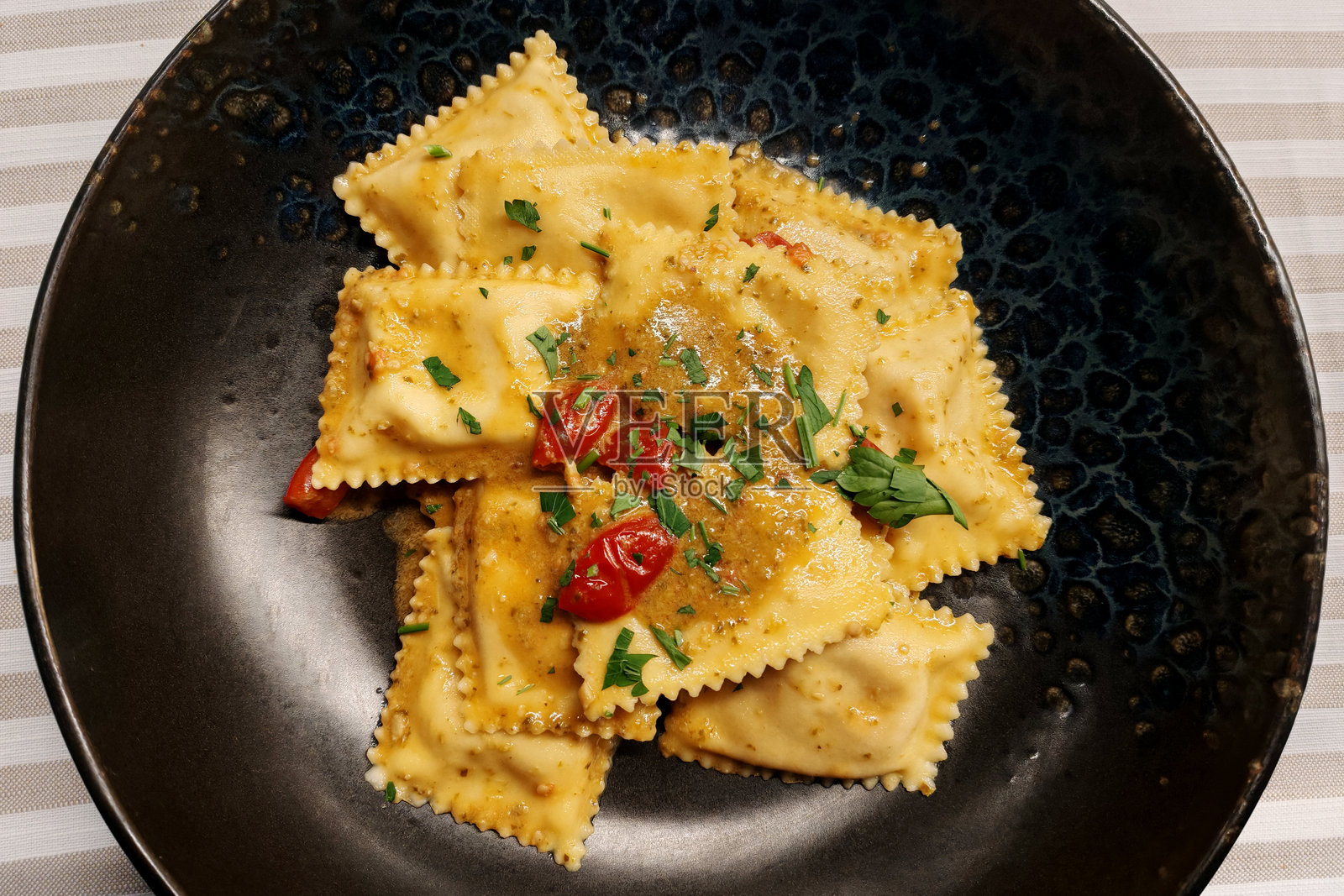 圆形黑盘中的鱼肉饺子照片摄影图片