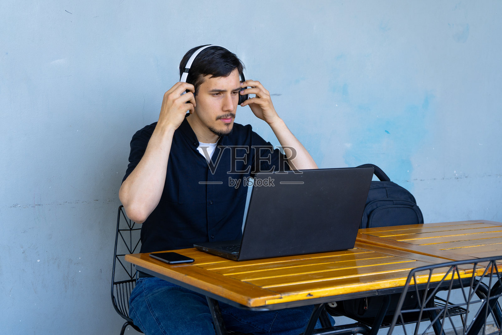 年轻人在咖啡馆戴上耳机，使用笔记本电脑照片摄影图片