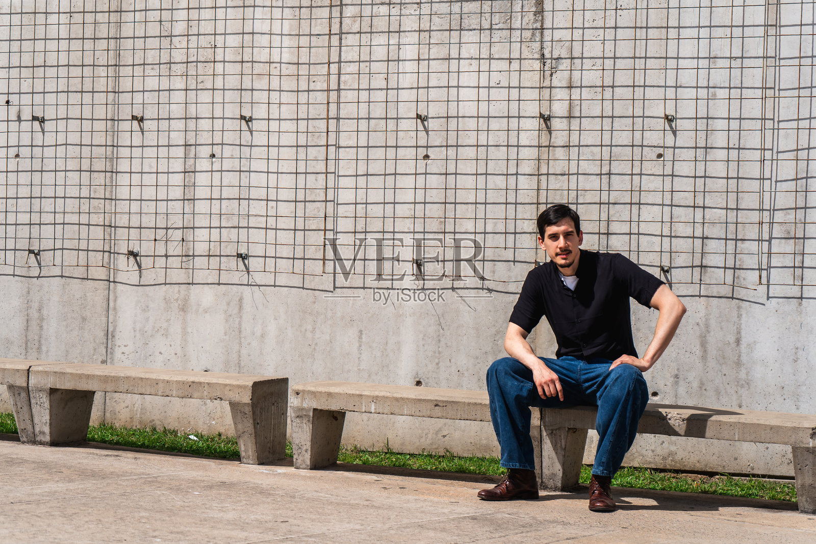 年轻的成年男子坐在城市环境的混凝土长椅上照片摄影图片