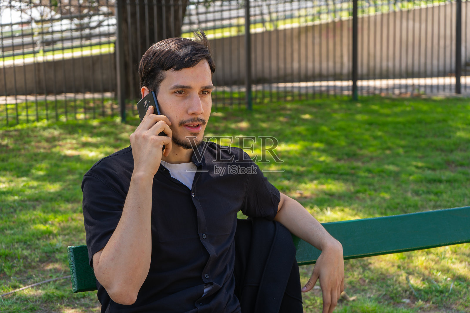 年轻男子在公园里打电话照片摄影图片