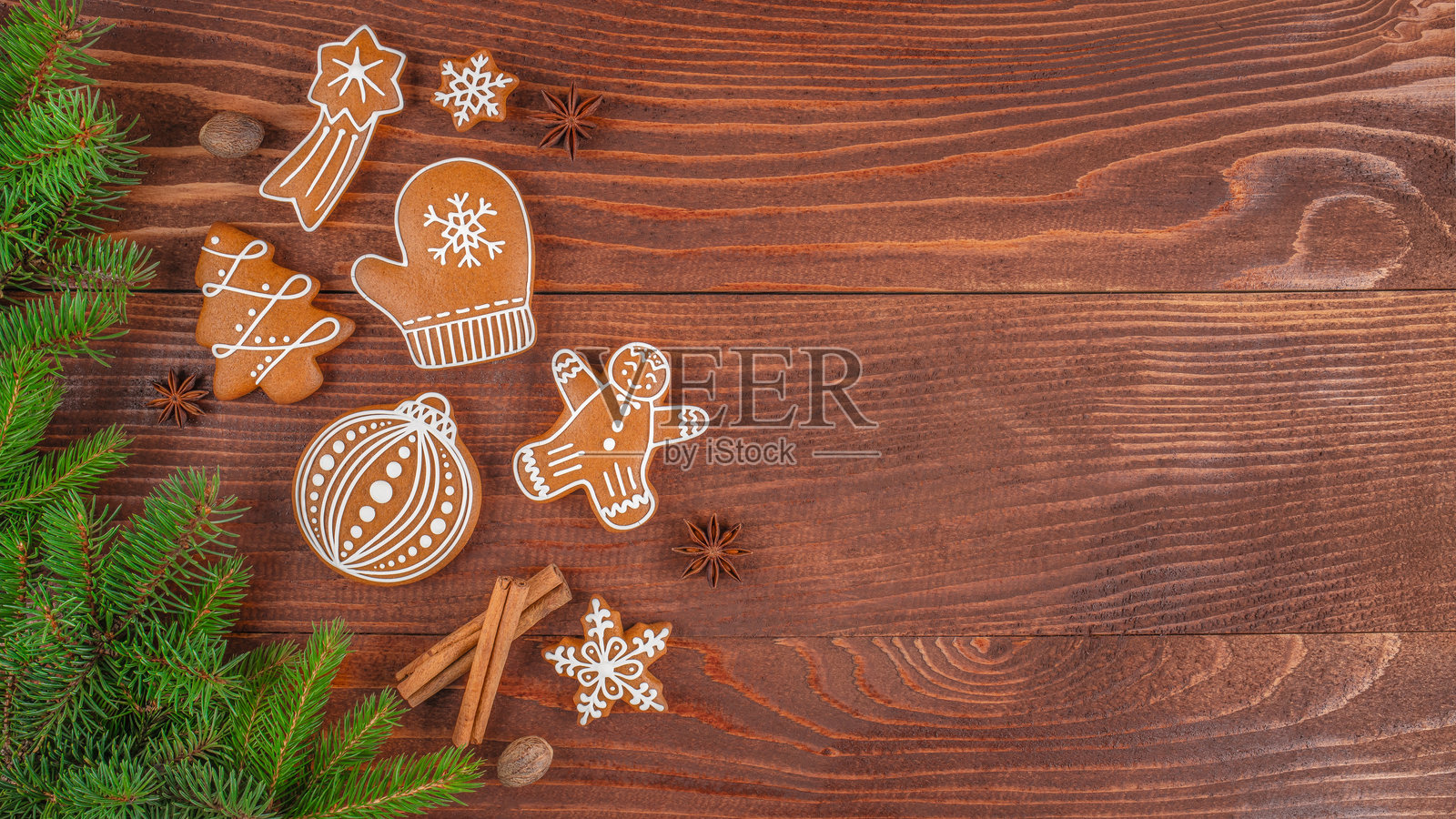 圣诞姜饼配糖霜、杉树枝和肉桂棒放在木桌上，节日背景，配有传统手工糖果和可供文字使用的空白空间照片摄影图片