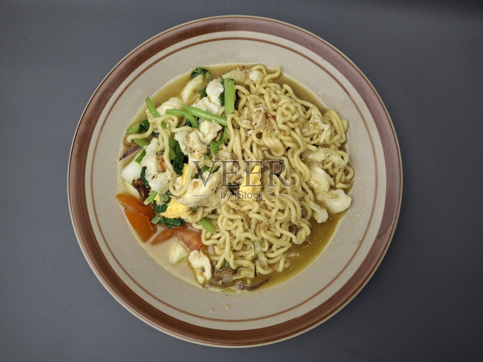 深灰色背景上的面条汤，配有蔬菜、鸡蛋和鸡肉配料照片摄影图片