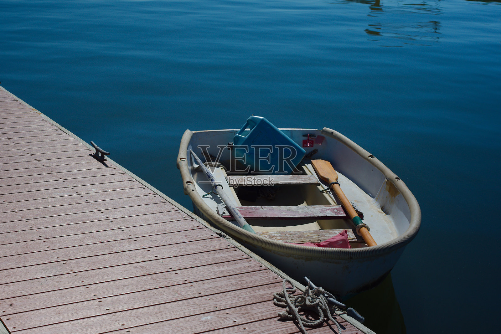阳光下的码头停靠着一艘饱经风霜的划艇，旁边放着船桨，构成一幅宁静的海滨景象，地点是佛罗里达州海湾港。照片摄影图片