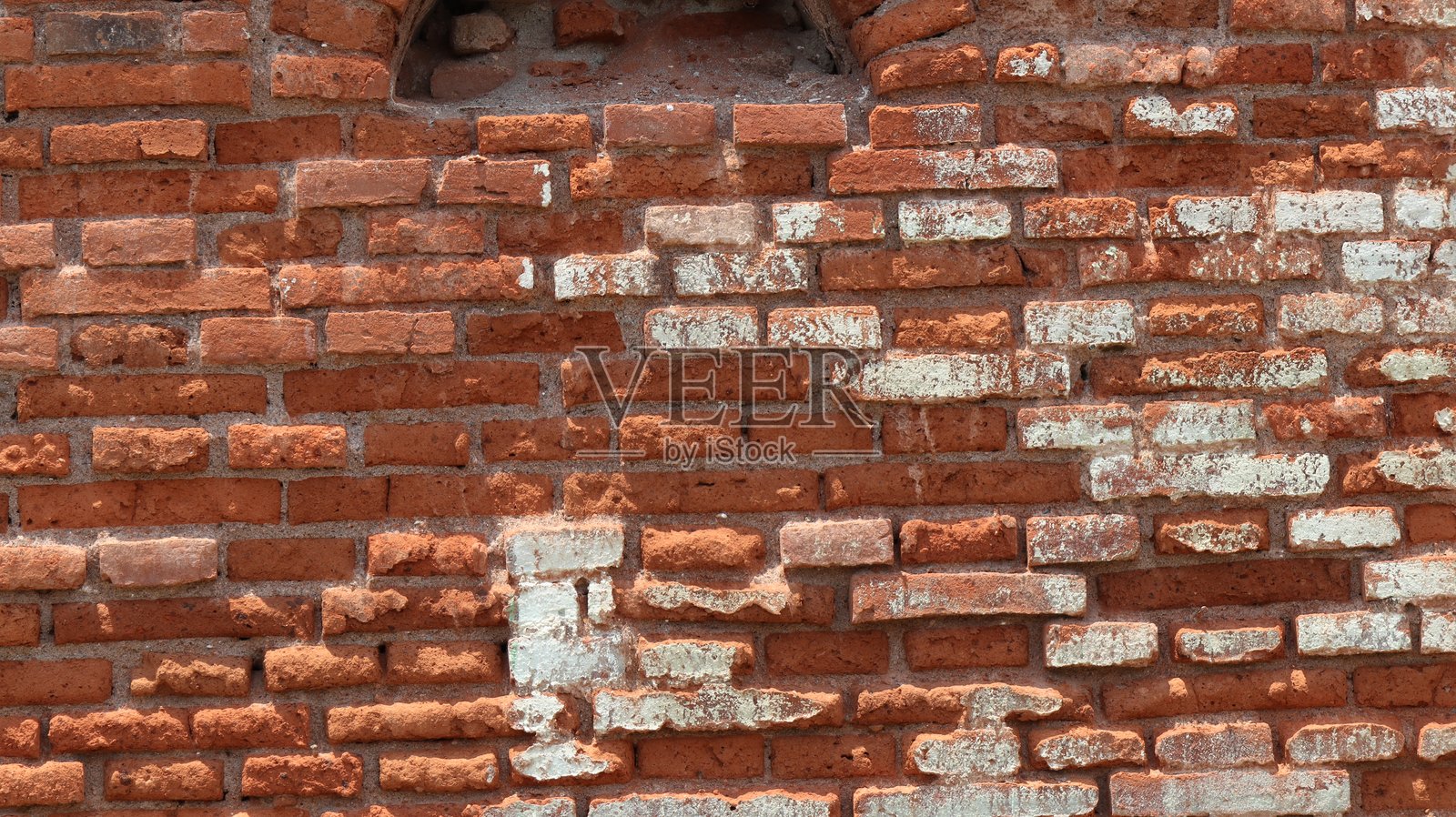 老旧的砖墙显示出岁月的痕迹和风化的迹象，砂浆剥落，红砖褪色。照片摄影图片