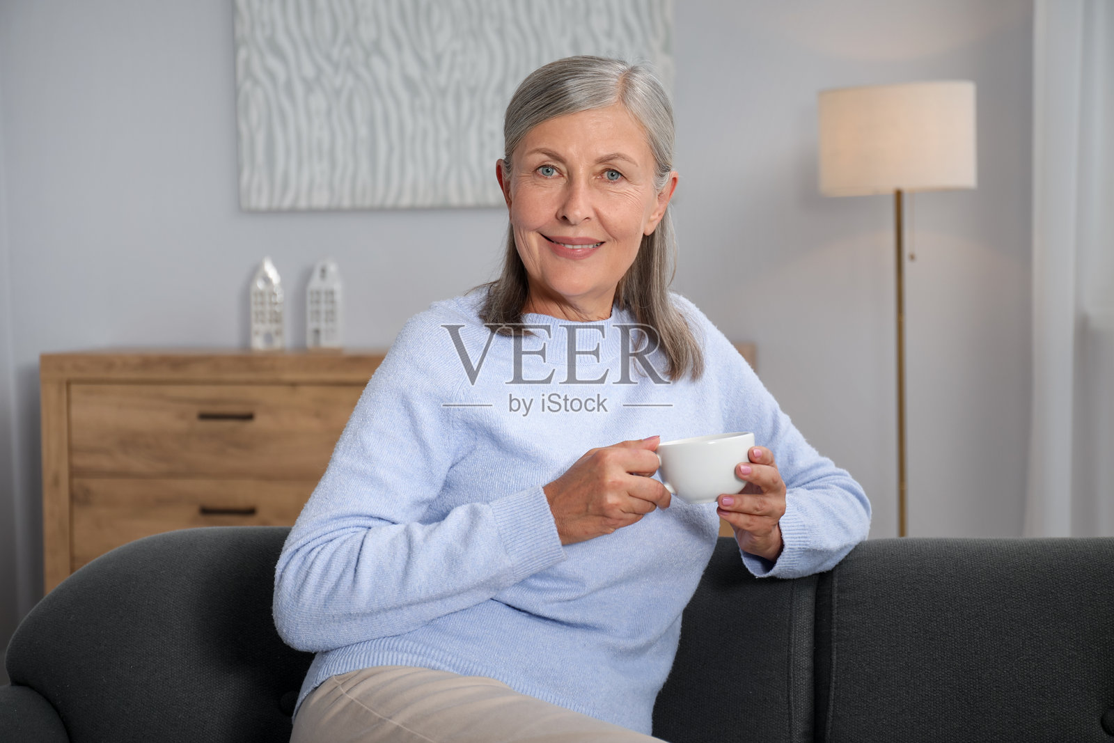 一位年长的女士在家里的沙发上喝茶照片摄影图片