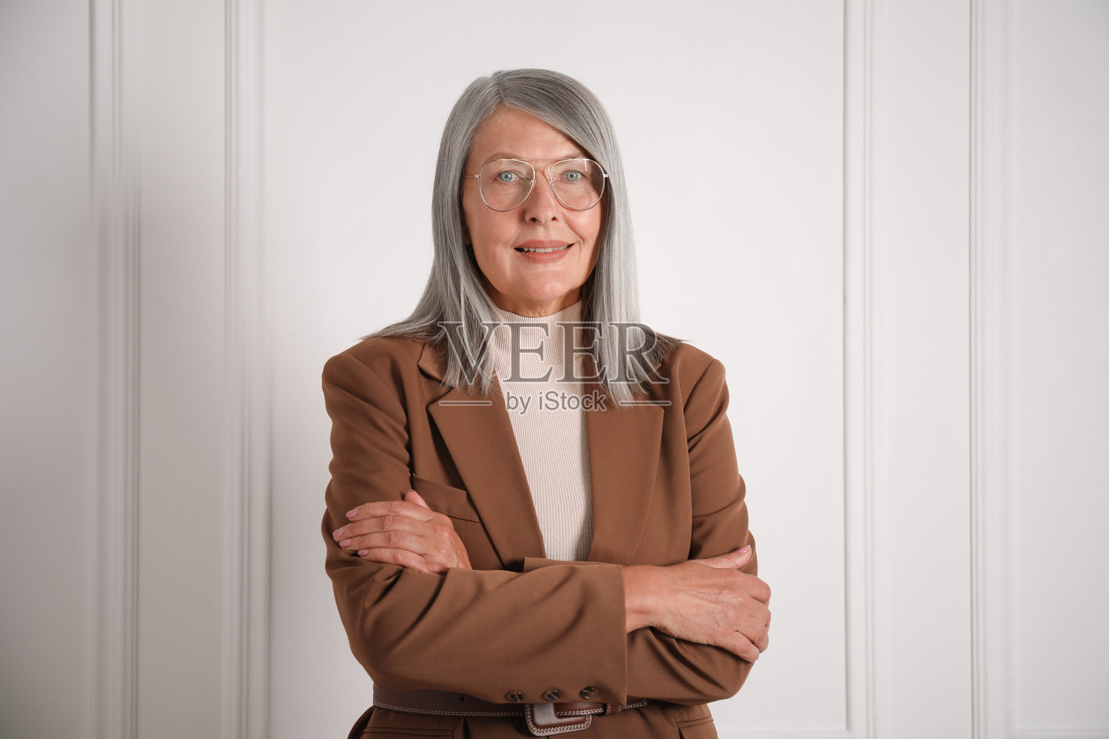 优雅年长女性肖像，背景为白色墙壁照片摄影图片