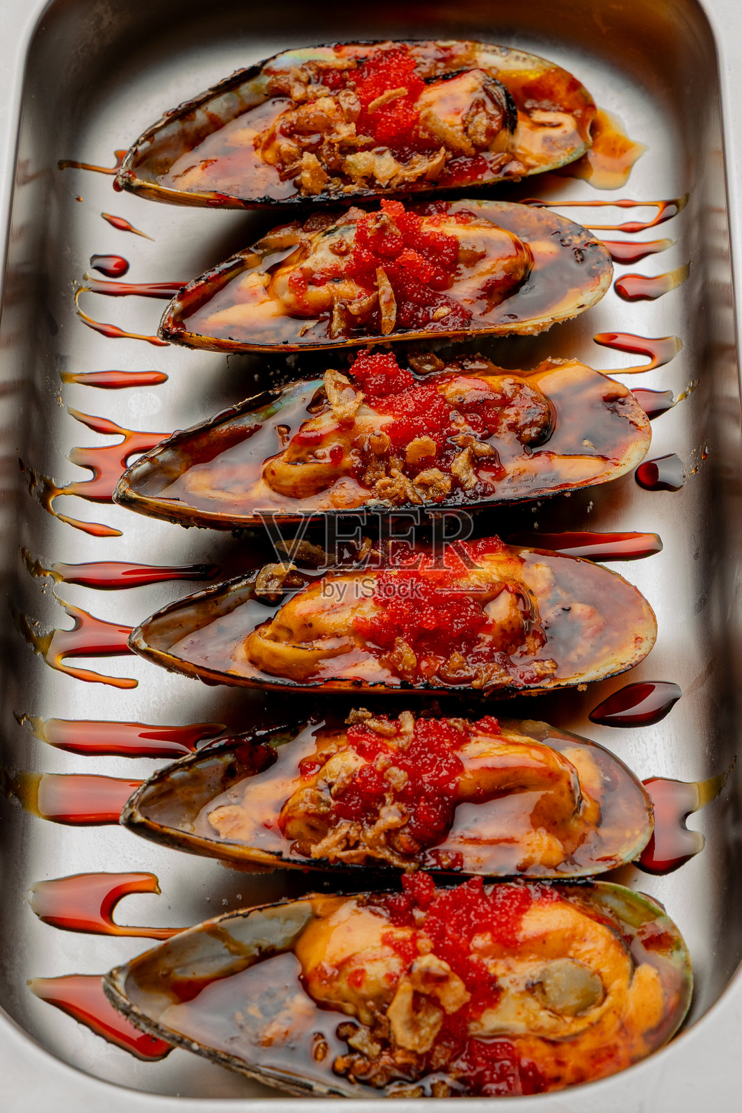 烤制的美味多汁贻贝盛放在精美的盘子里，孤立的照片摄影图片