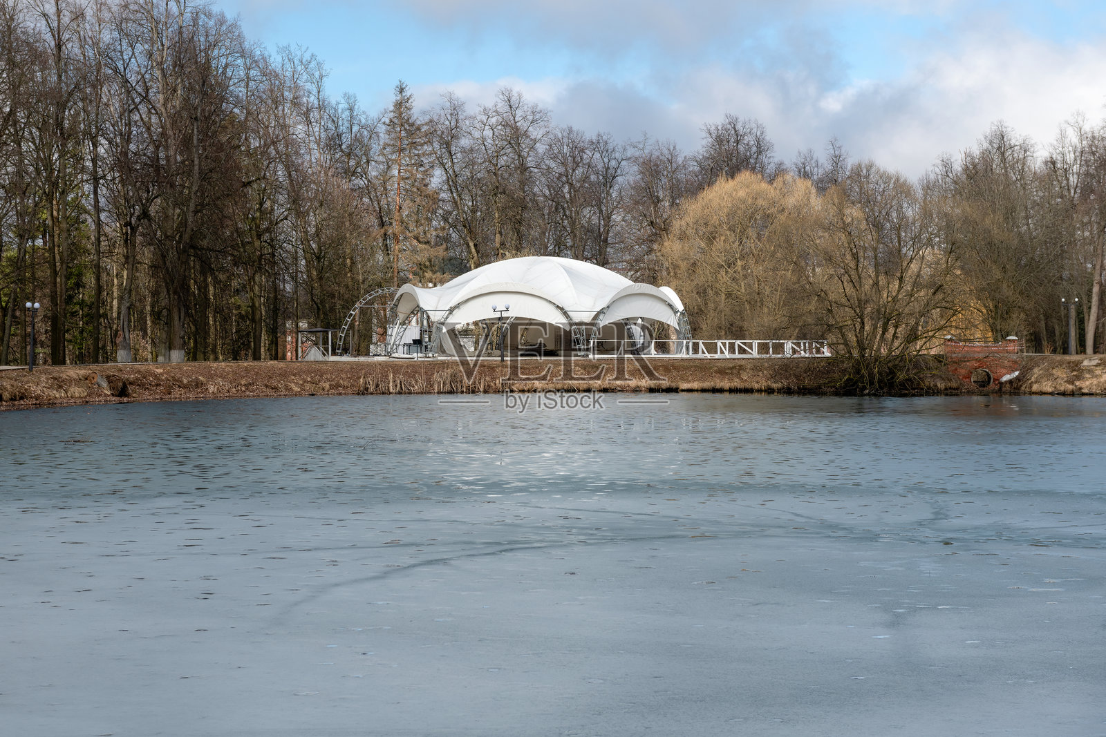 城市公园池塘的春日景象，岸边是一家夏季餐厅的建筑照片摄影图片