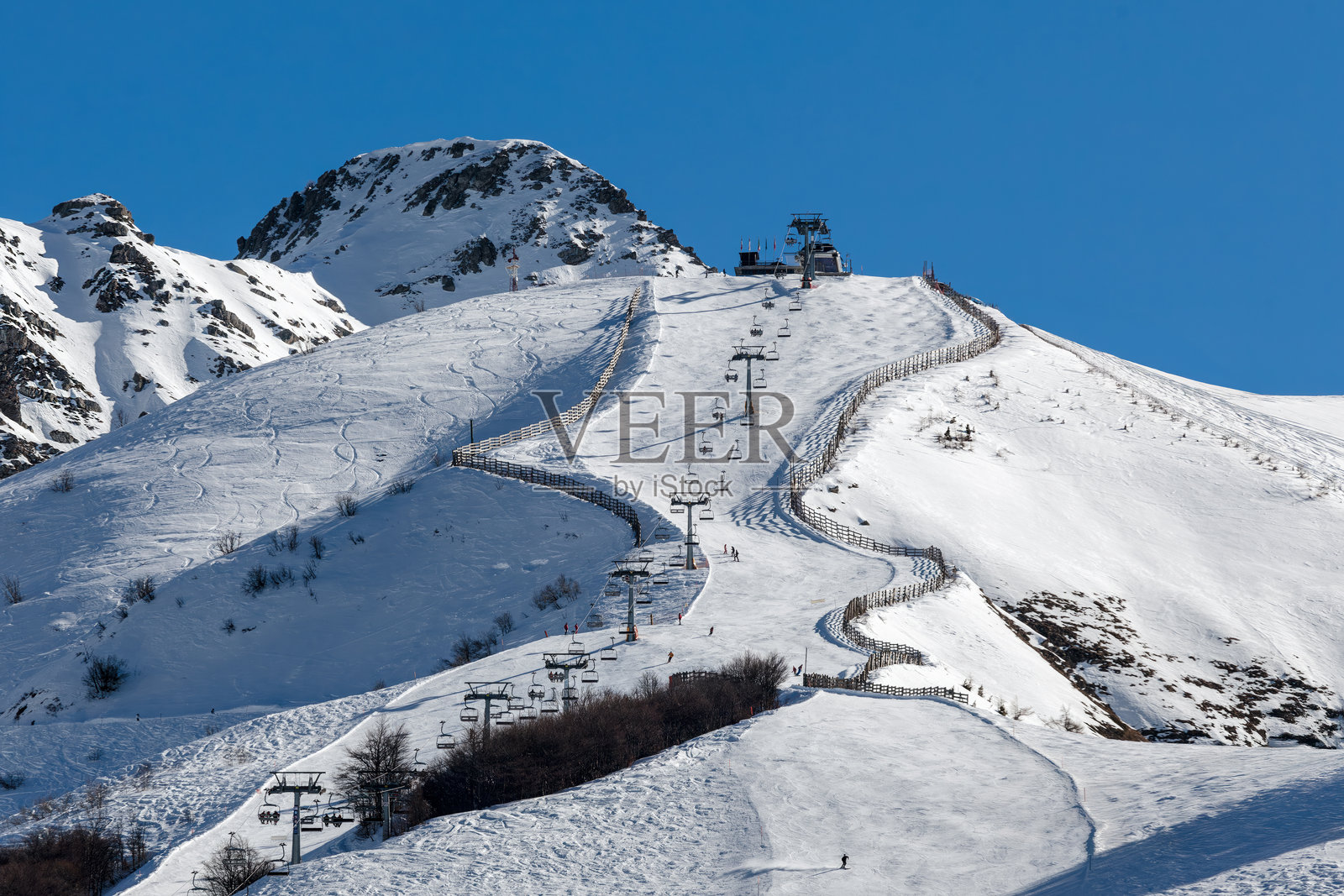 意大利风景如画的冬季山坡滑雪场，四周环绕着崎岖的山峰，天空湛蓝。照片摄影图片