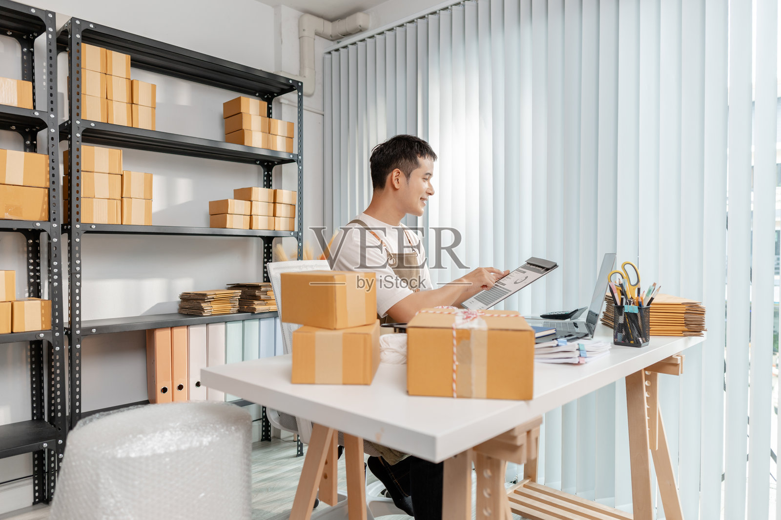 年轻企业家管理在线业务，准备包裹并处理电子商务运营，代表数字市场、初创企业增长和现代零售战略。照片摄影图片