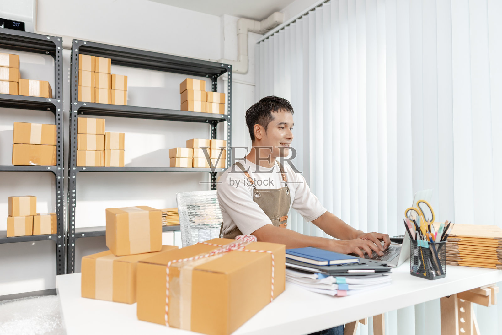 年轻的企业家管理在线业务，准备包裹并处理电子商务运营，代表着数字市场、初创企业增长和现代零售策略。照片摄影图片