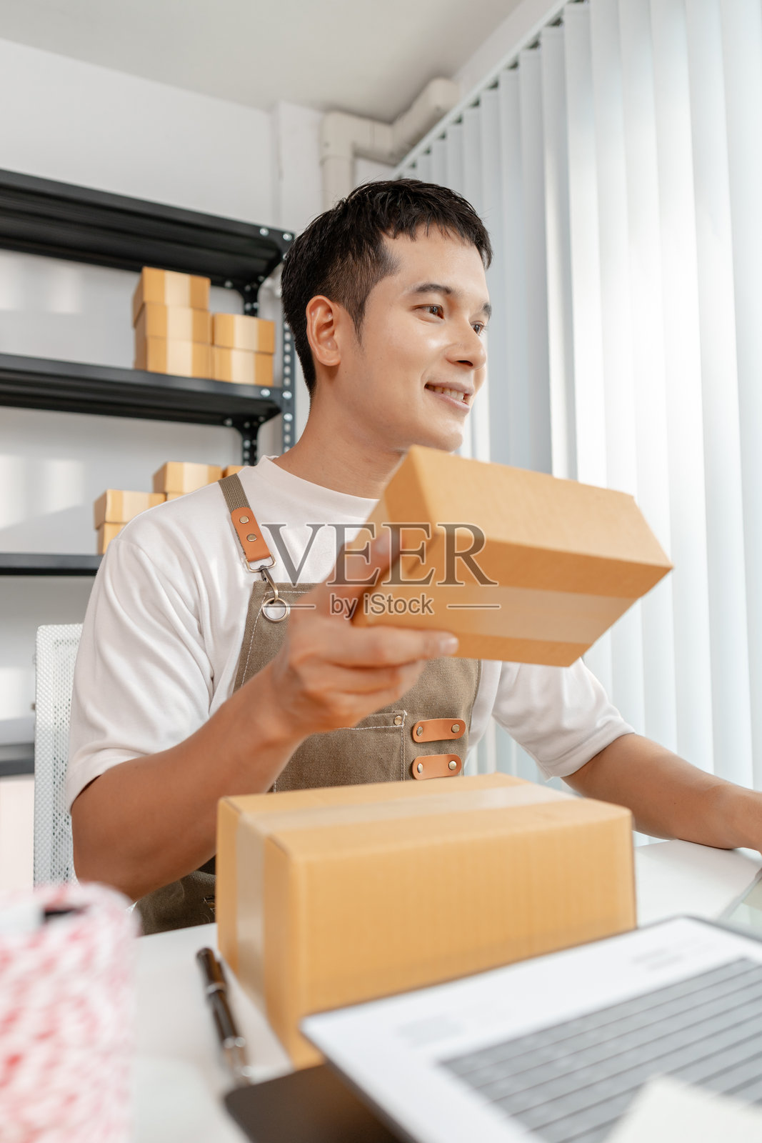 电子商务概念，一位创业者正在处理商品，展示在线商店运营、数字零售解决方案以及创新在全球小企业发展中的作用。照片摄影图片